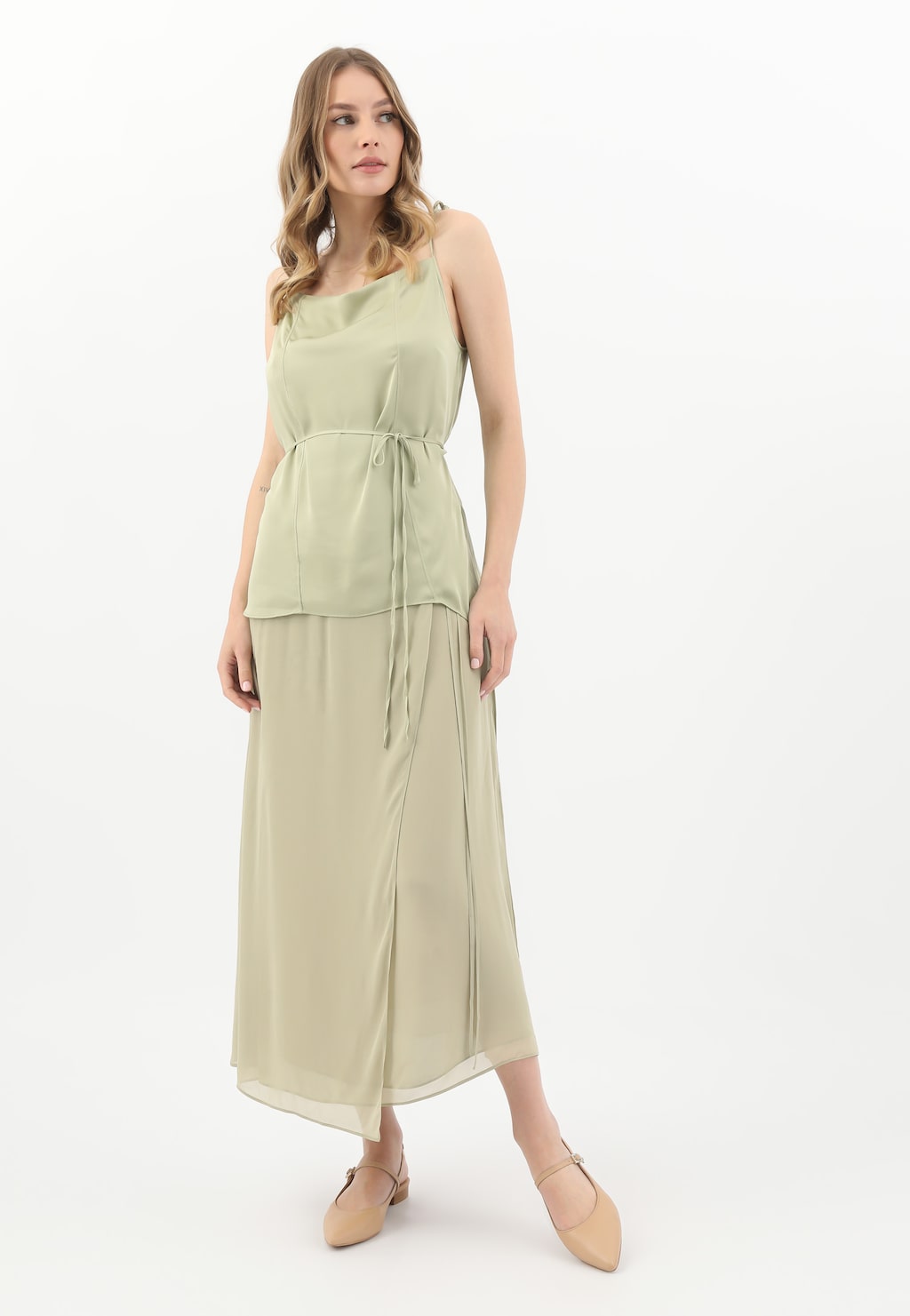 Osoba w jasnobeżowej sukni prezentująca beżowe baleriny damskie Wojas model 44046-54 z odkrytą piętą, idealne do eleganckich stylizacji.