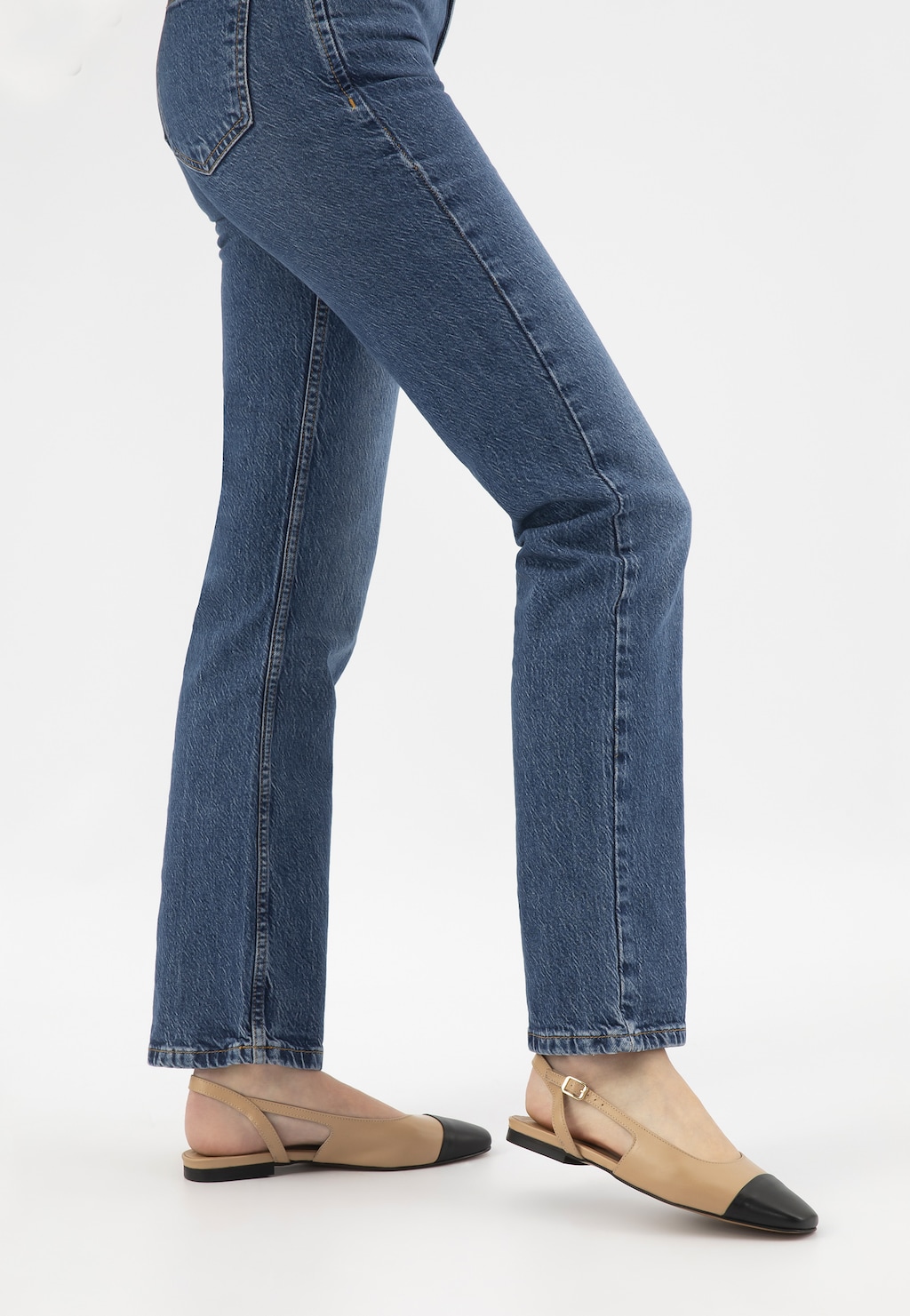 Dwukolorowe baleriny damskie Wojas model 44032-54 z beżowym korpusem i czarnym noskiem, z odkrytą piętą, prezentowane na nogach w niebieskich dżinsach.