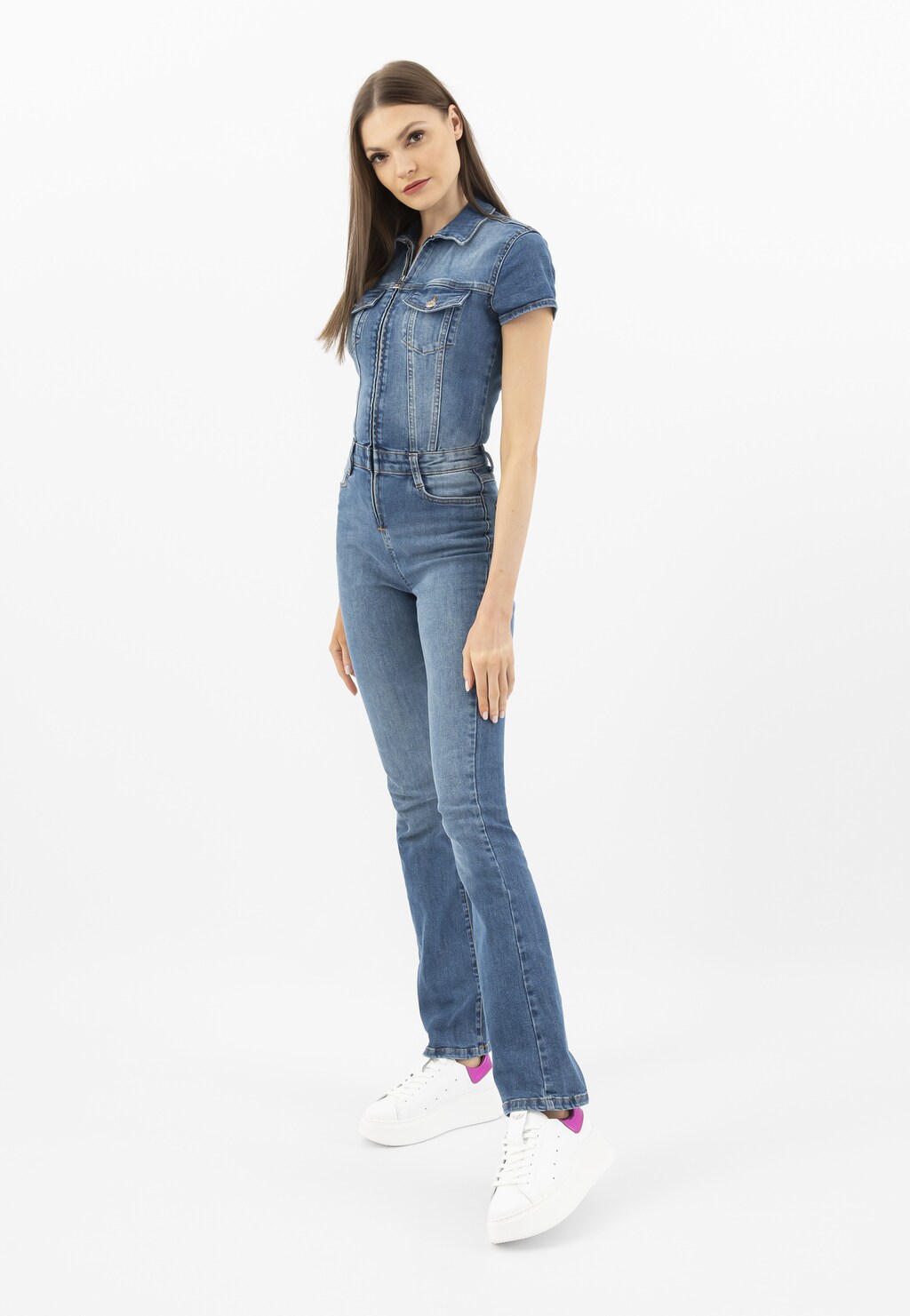 Modelka w jeansowym kombinezonie prezentująca białe trampki Wojas model 46285-75 z charakterystyczną różową metaliczną wstawką, idealne do casualowych stylizacji.