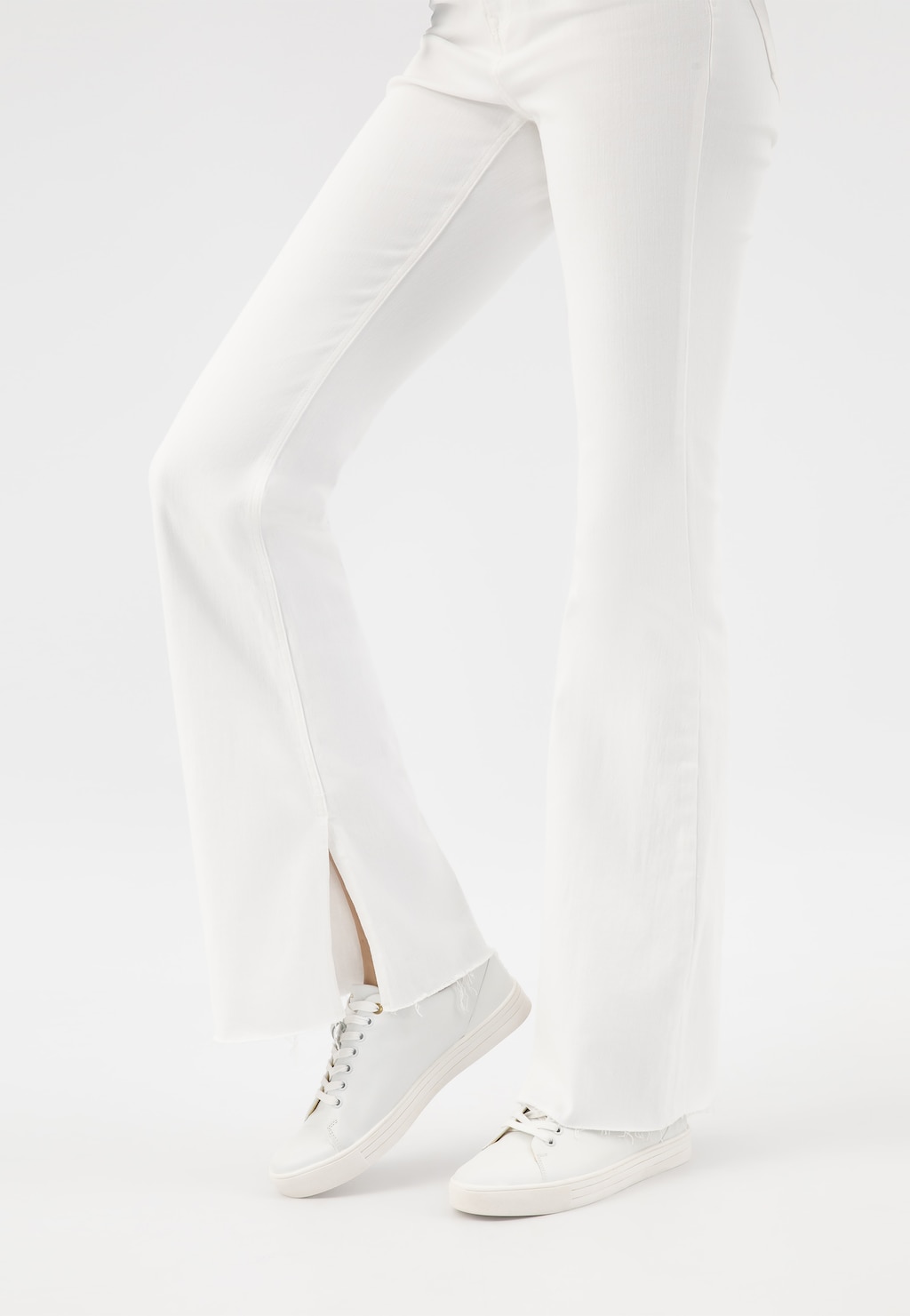 Białe trampki damskie Wojas 46019-59 ze skóry licowej na nogach modelki w białych spodniach, widok z boku pokazujący klasyczny, minimalistyczny design obuwia.