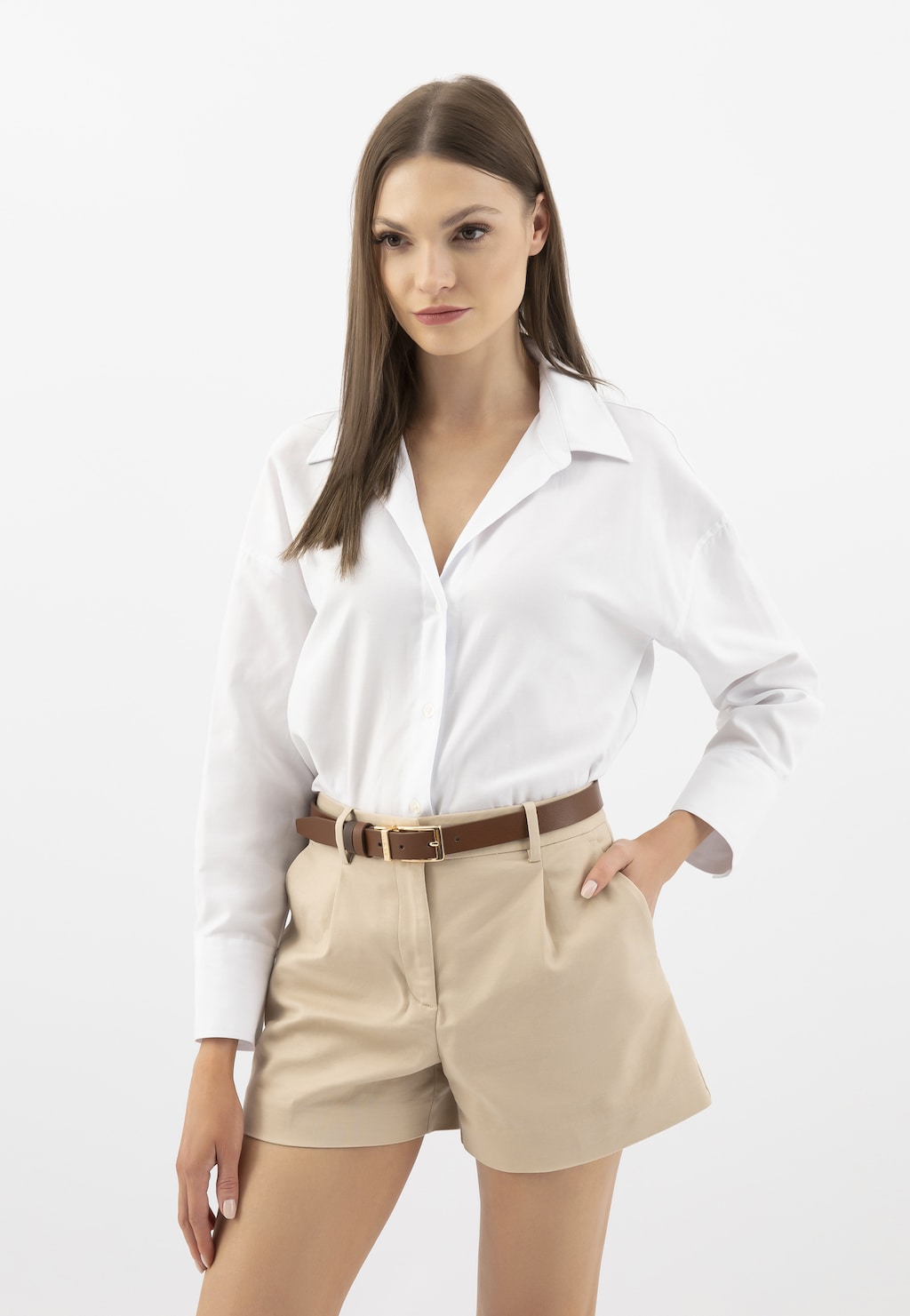 Modelka w białej koszuli i beżowych szortach prezentuje dwustronny brązowy pasek damski Wojas 93102-52 ze złotą klamrą, wykonany ze skóry licowej.