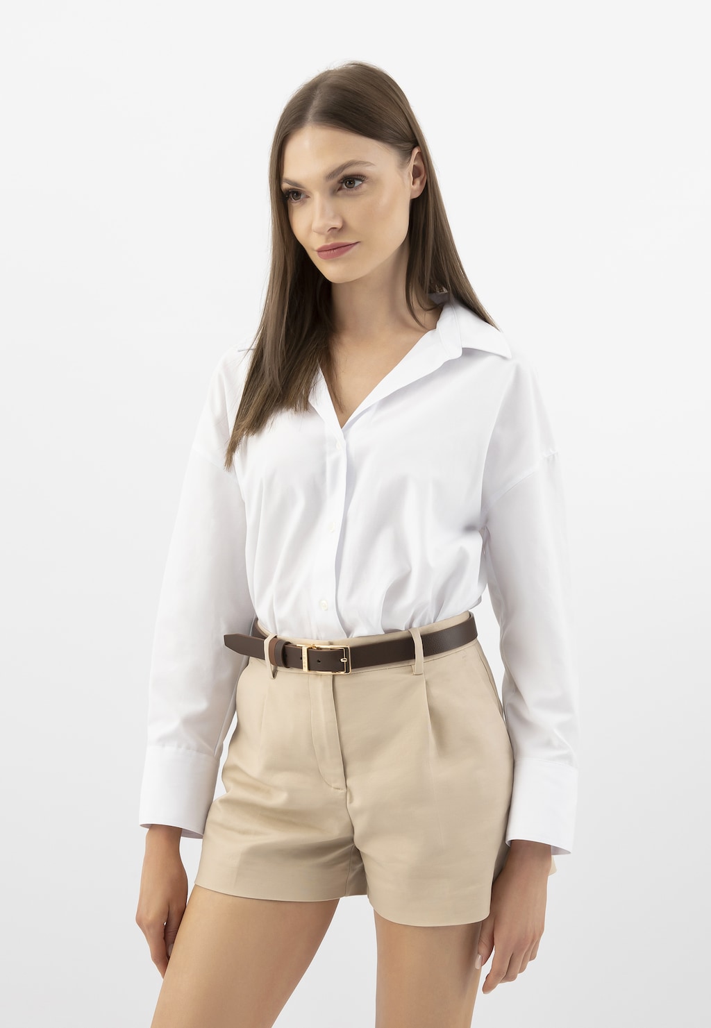 Elegancki strój z dwustronnym brązowym paskiem Wojas 93102-52 ze złotą klamrą, podkreślającym stylizację z białą koszulą i beżowymi szortami.