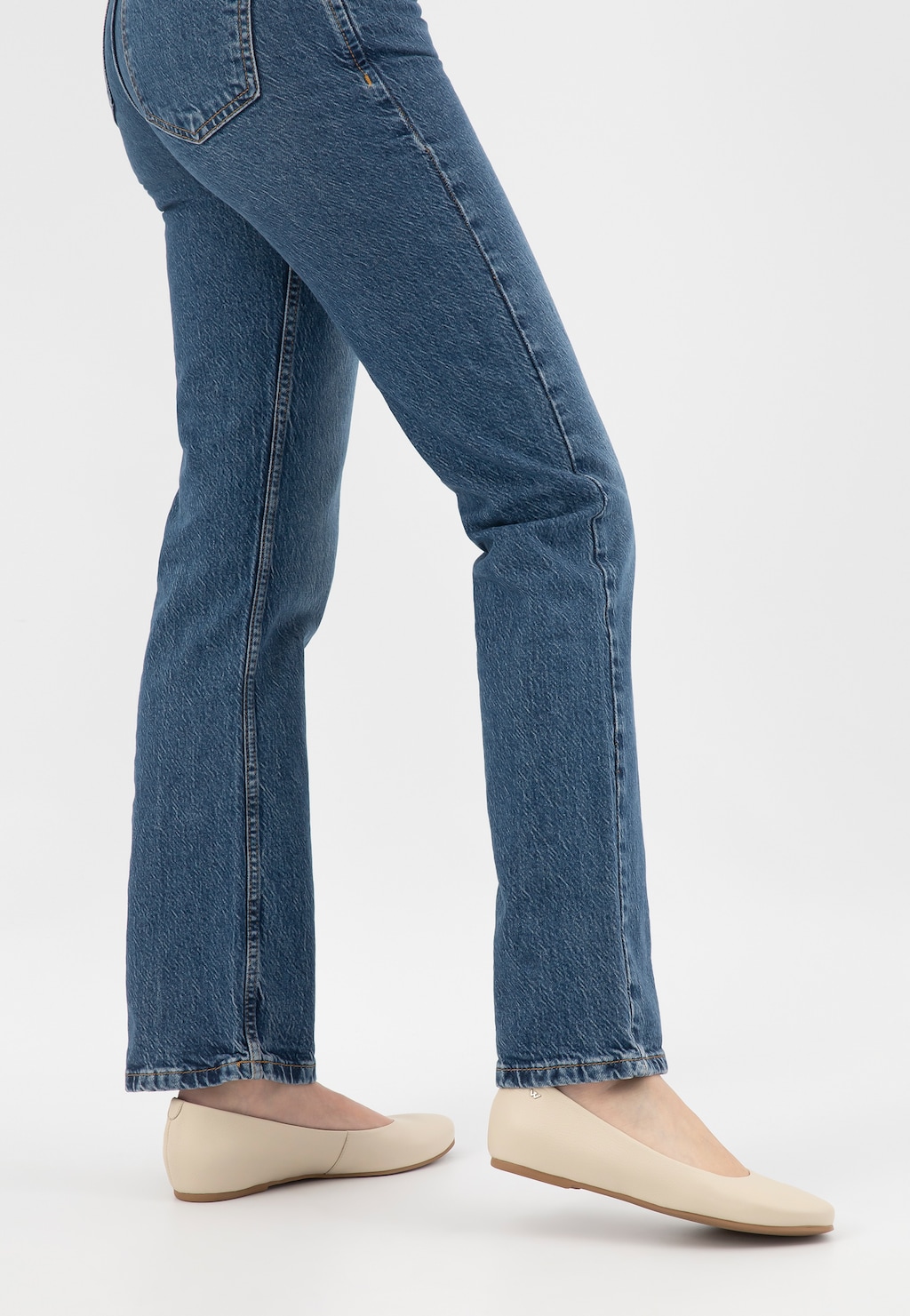 Beżowe skórzane baleriny damskie Wojas model 44005-54 noszone do klasycznych jeansów. Widok z boku pokazujący elegancki, płaski fason obuwia idealny do codziennych stylizacji.