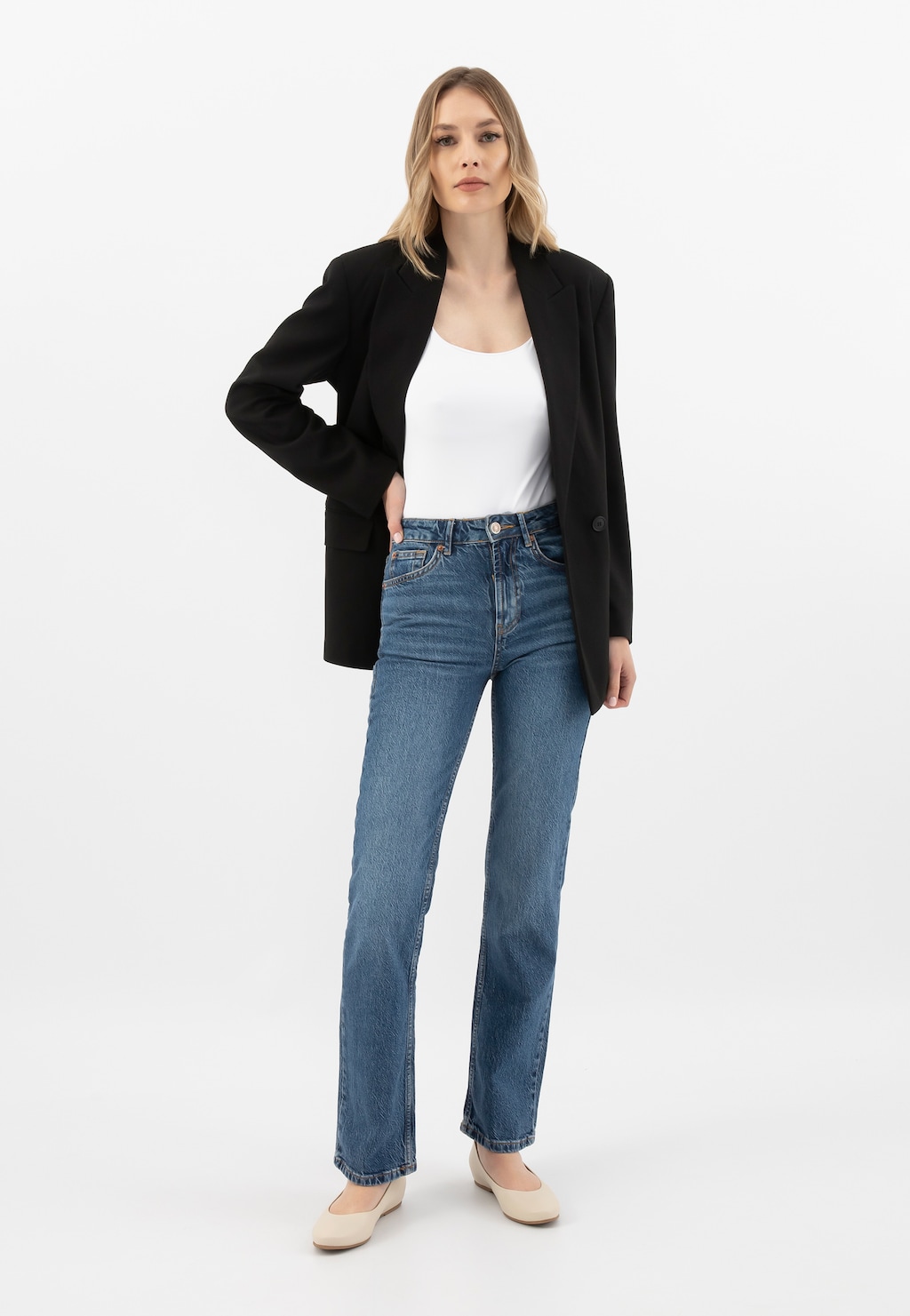 Modelka w eleganckiej stylizacji z czarnym żakietem, białym topem i jeansami, prezentująca beżowe skórzane baleriny damskie marki Wojas model 44005-54.