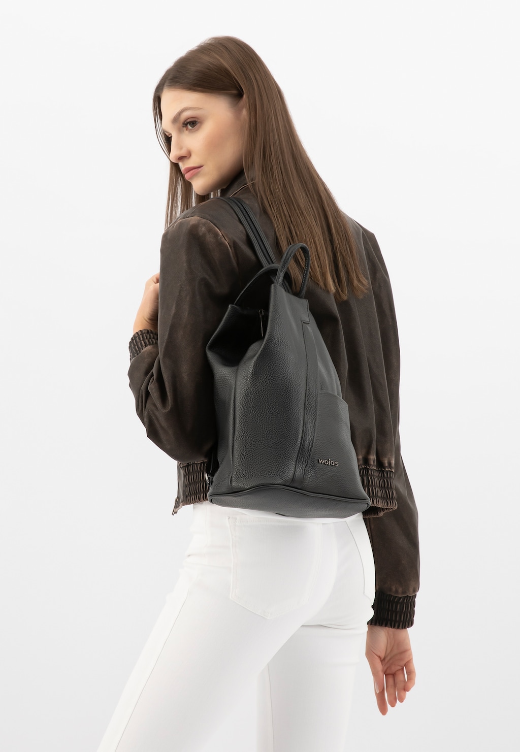 Czarny plecak Wojas 80083-51 ze skóry licowej noszony na plecach przez osobę w brązowej kurtce i białych spodniach, ukazujący elegancki design i teksturę skóry.