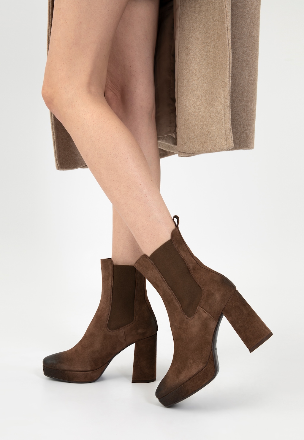 Eleganckie brązowe sztyblety damskie Wojas model 55212-62 na wysokim słupku i platformie, noszone z beżową spódnicą, ukazane z boku na nodze modelki.