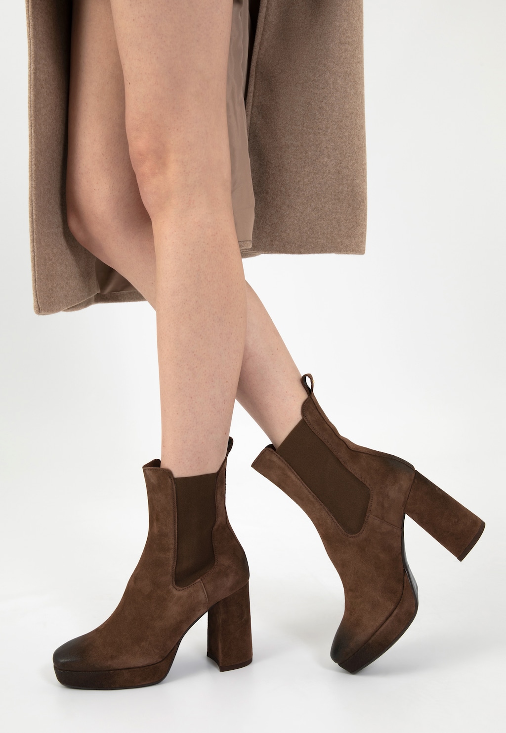 Brązowe sztyblety damskie Wojas model 55212-62 na wysokim słupku, prezentowane na nogach osoby ubranej w beżowy płaszcz, widok z profilu pokazujący elegancki design obuwia.