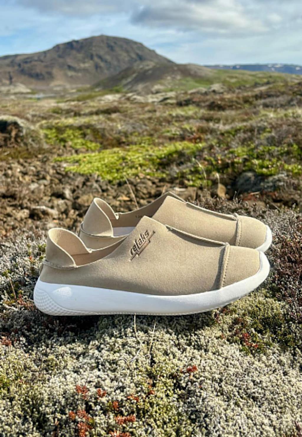 Beżowe półbuty RELAKS model R46168-14 na lekkiej białej podeszwie, sfotografowane na naturalistycznym górskim terenie z malowniczym szczytem w tle.