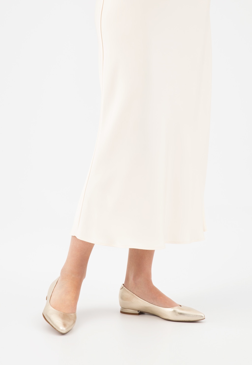 Złote baleriny damskie Wojas model 44033-58 na niskim obcasie, prezentowane na nogach w białej sukience, widok z przodu ukazujący elegancki, spiczasty czubek.