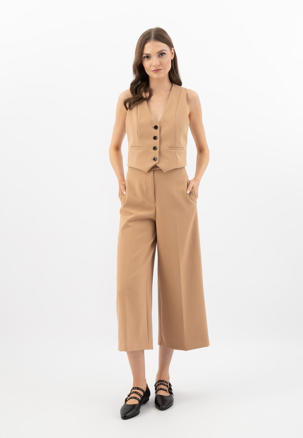 Elegancki beżowy strój biznesowy z kamizelką i szerokimi spodniami kulotami, uzupełniony balerynami Wojas model 44042-51 w stylu Mary Jane z trzema czarnymi paskami.