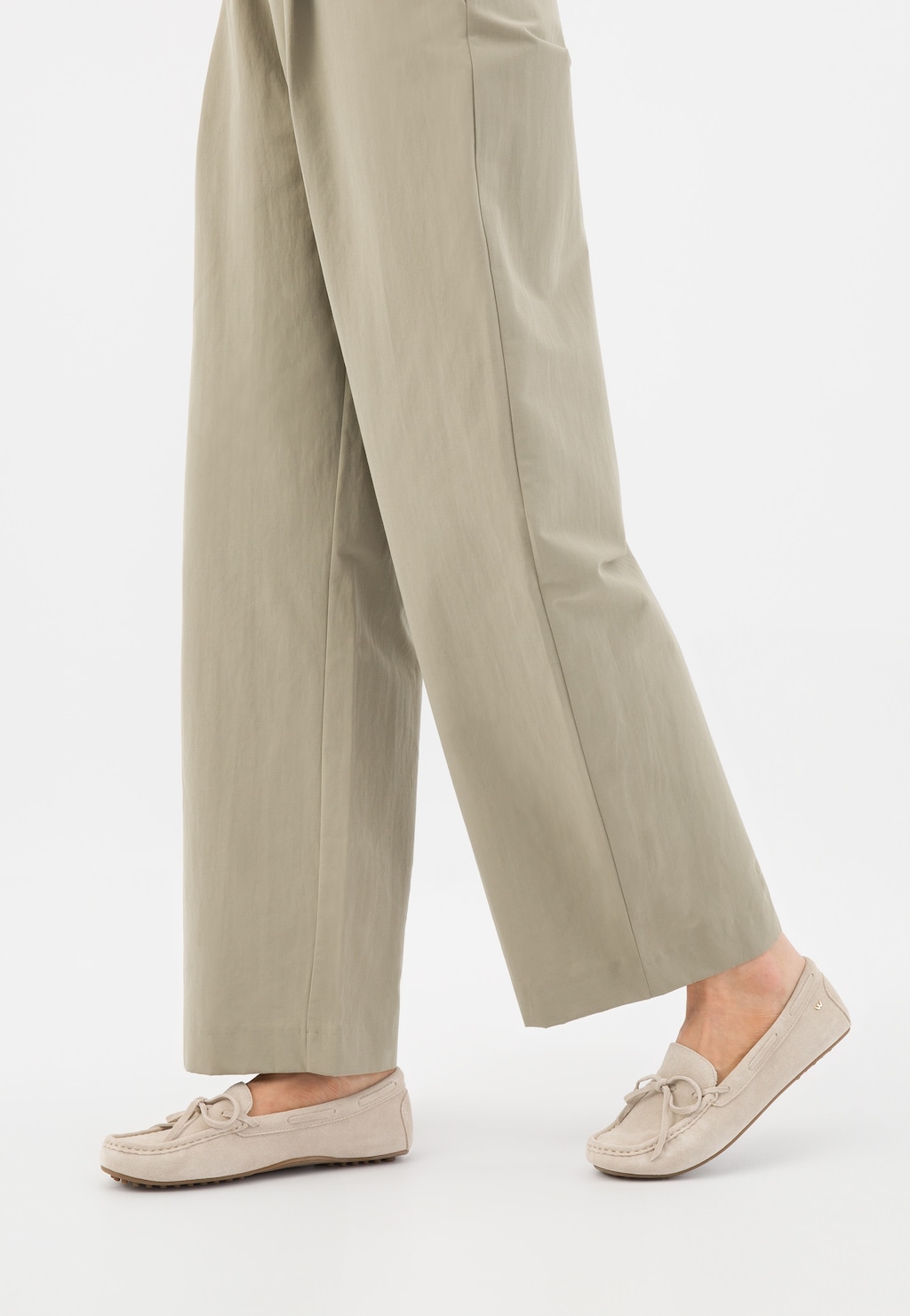 Beżowe mokasyny damskie Wojas model 46270-64 z ozdobnymi wypustkami na podeszwie, noszone do eleganckich beżowych spodni. Widok boczny butów na stopie.