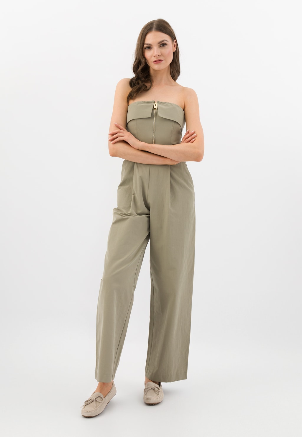 Modelka w oliwkowym kombinezonie bez ramiączek, prezentująca beżowe mokasyny damskie Wojas model 46270-64 z charakterystycznymi wypustkami na podeszwie, idealne do eleganckich stylizacji.