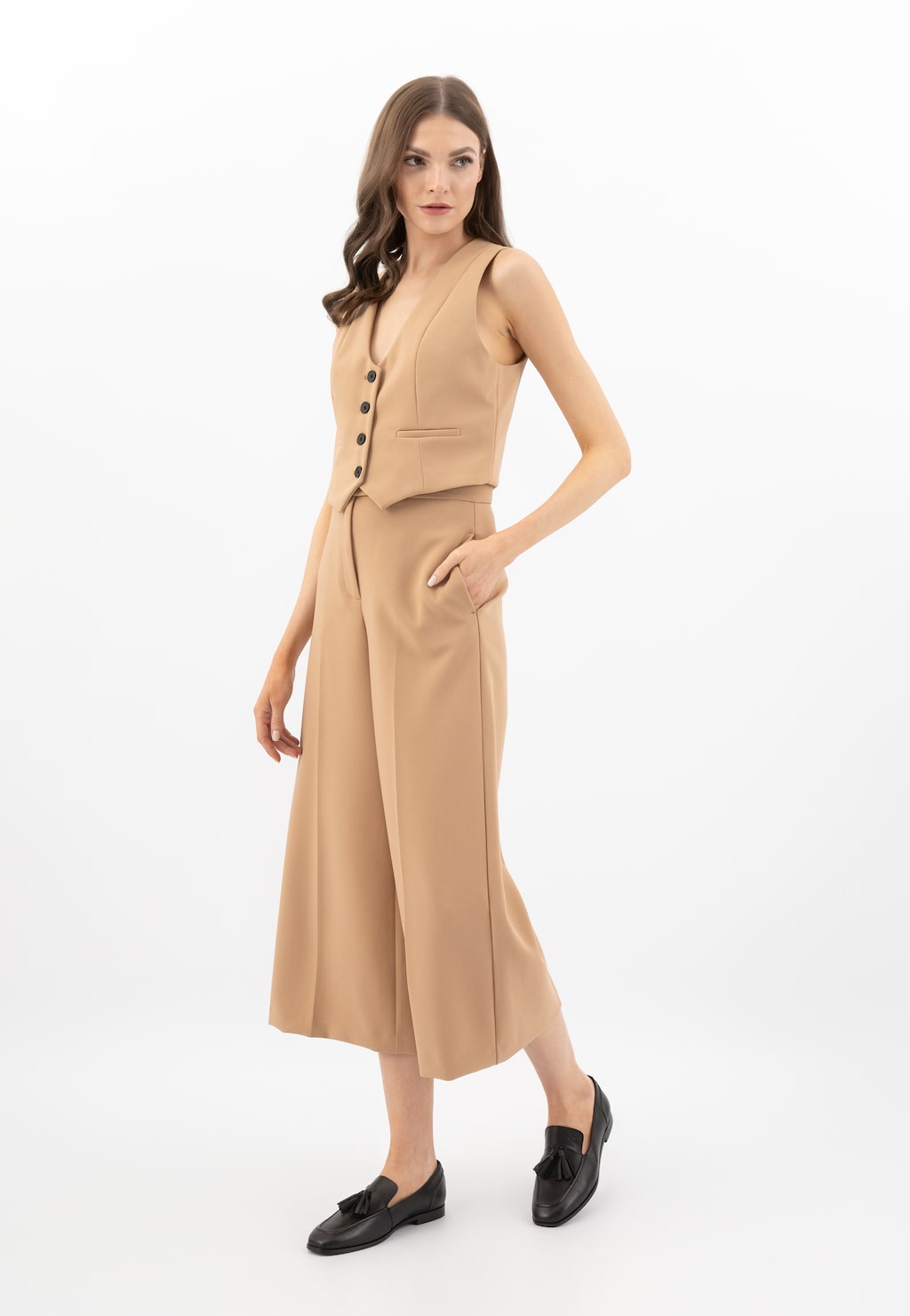 Model w eleganckim beżowym komplecie z kamizelką i spodniami culotte, prezentująca czarne skórzane lordsy damskie Wojas z chwostem, model 46272-51.