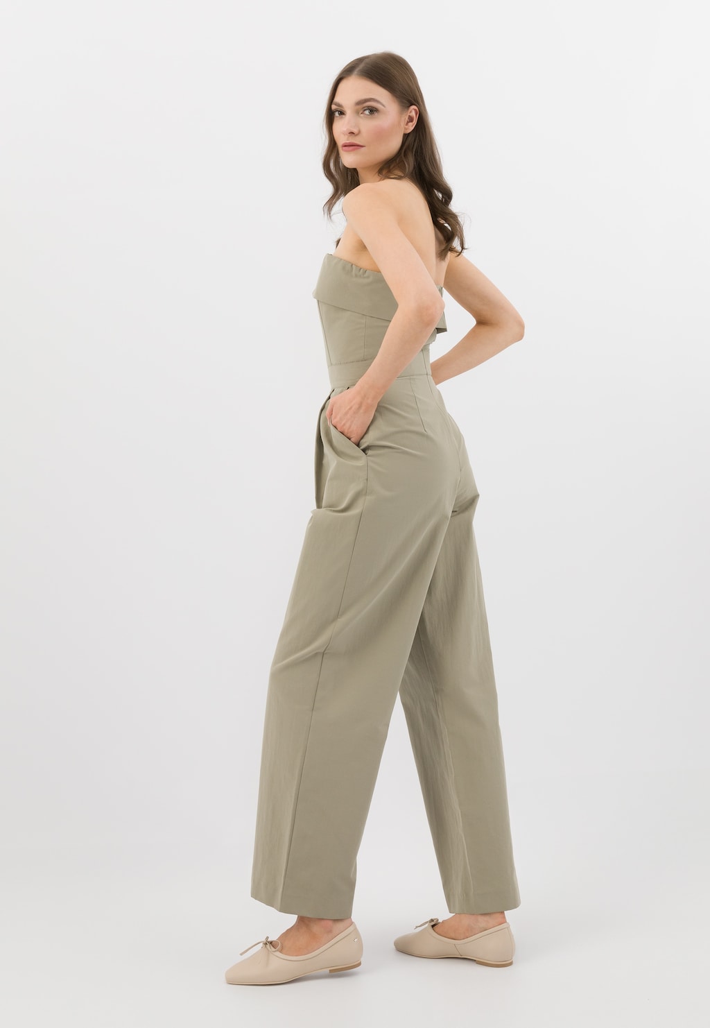 Modelka w oliwkowym kombinezonie prezentuje beżowe półbuty damskie Wojas model 46300-54 z charakterystycznym noskiem w szpic, widoczne z boku.
