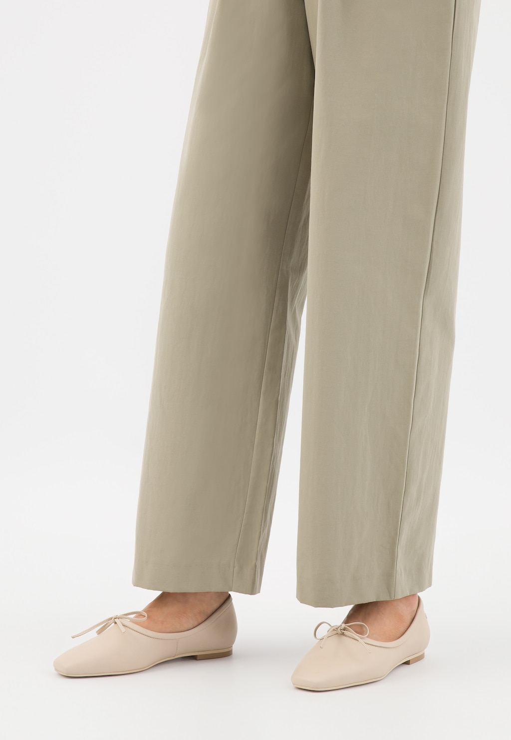 Beżowe półbuty damskie Wojas model 46300-54 ze szpiczastym noskiem i delikatną kokardką, widoczne na nogach osoby w jasnobeżowych, szerokich spodniach.
