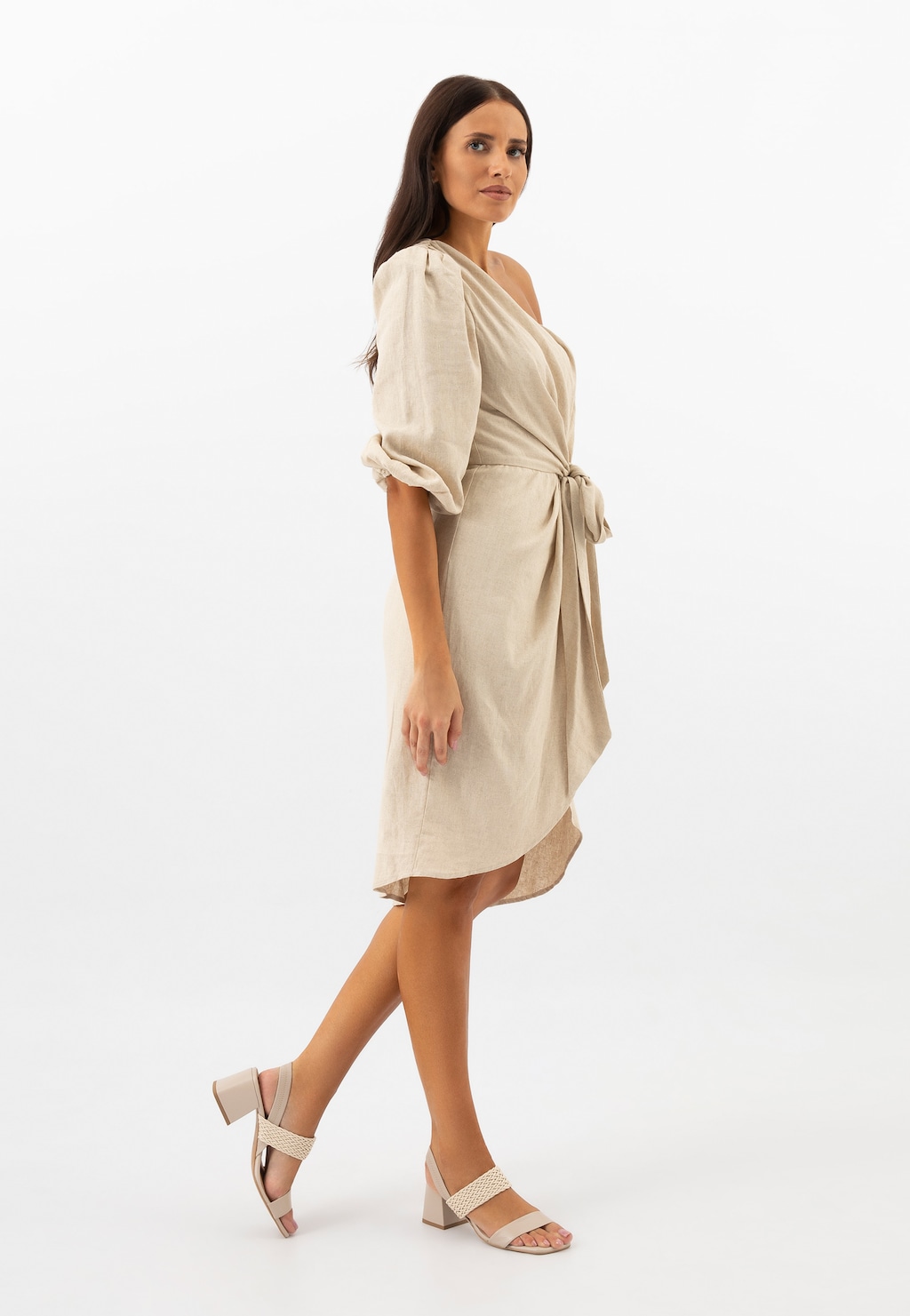 Modelka w beżowej sukience prezentuje beżowe sandały Wojas model 76165-84 na słupku z plecionym paskiem. Eleganckie obuwie doskonale komponuje się z letnią stylizacją.