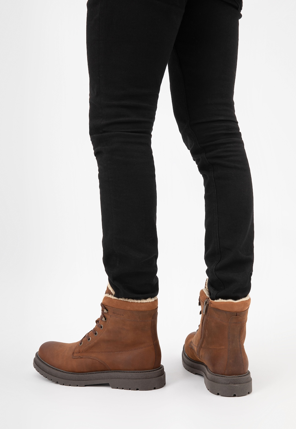 Brązowe męskie trzewiki Wojas 24077-93 typu bikery z ociepleniem, zaprezentowane na nogach w czarnych spodniach. Buty mają grubą podeszwę i widoczne sznurowanie.