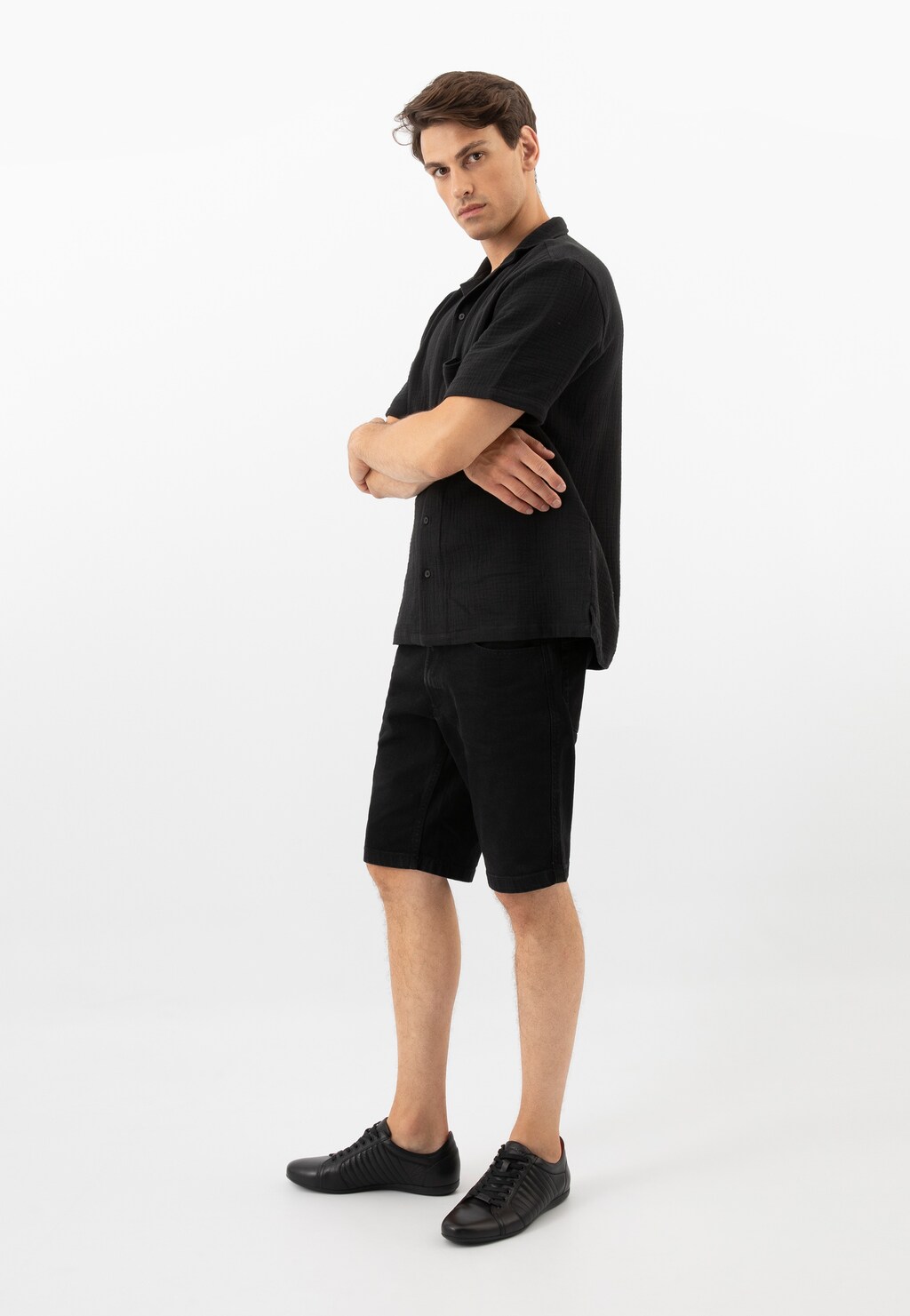 Model w czarnym zestawie prezentujący czarne męskie półbuty Wojas model 9012-51. Eleganckie buty widoczne są z boku, doskonale komponując się z casualowym strojem.