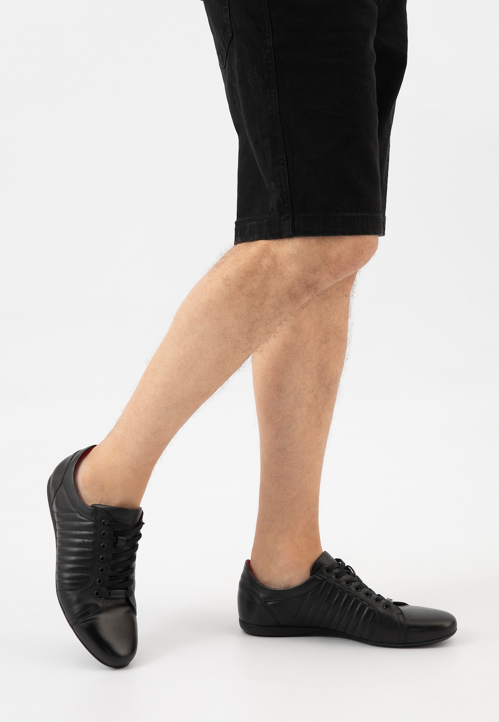 Czarne męskie półbuty Wojas model 9012-51 z przeszyciami, noszone z czarnymi szortami. Widok z profilu pokazujący elegancki, sportowy charakter butów ze sznurowaniem.
