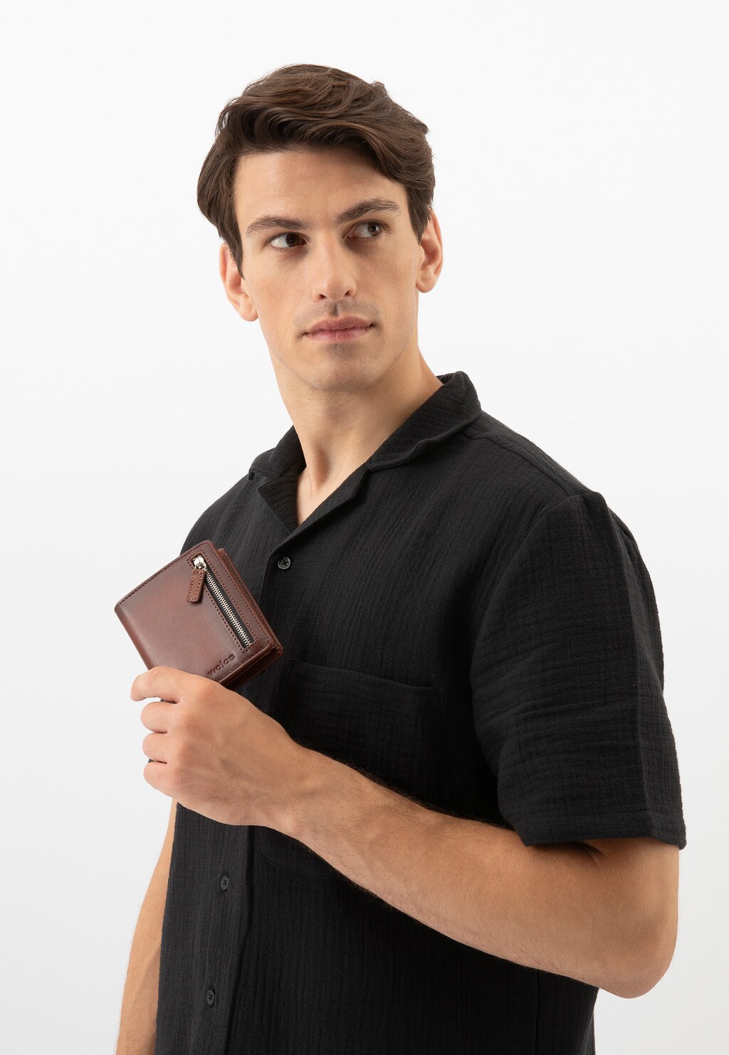 Elegancki brązowy portfel męski Wojas model 9959-52 trzymany przez mężczyznę w czarnej koszuli. Widoczne zamki i stylowe wykończenie portfela.