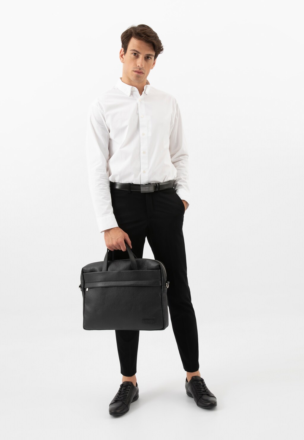 Elegancka czarna skórzana torba męska Wojas 80071-51 z przegrodą na laptopa trzymana przez mężczyznę w białej koszuli i czarnych spodniach.