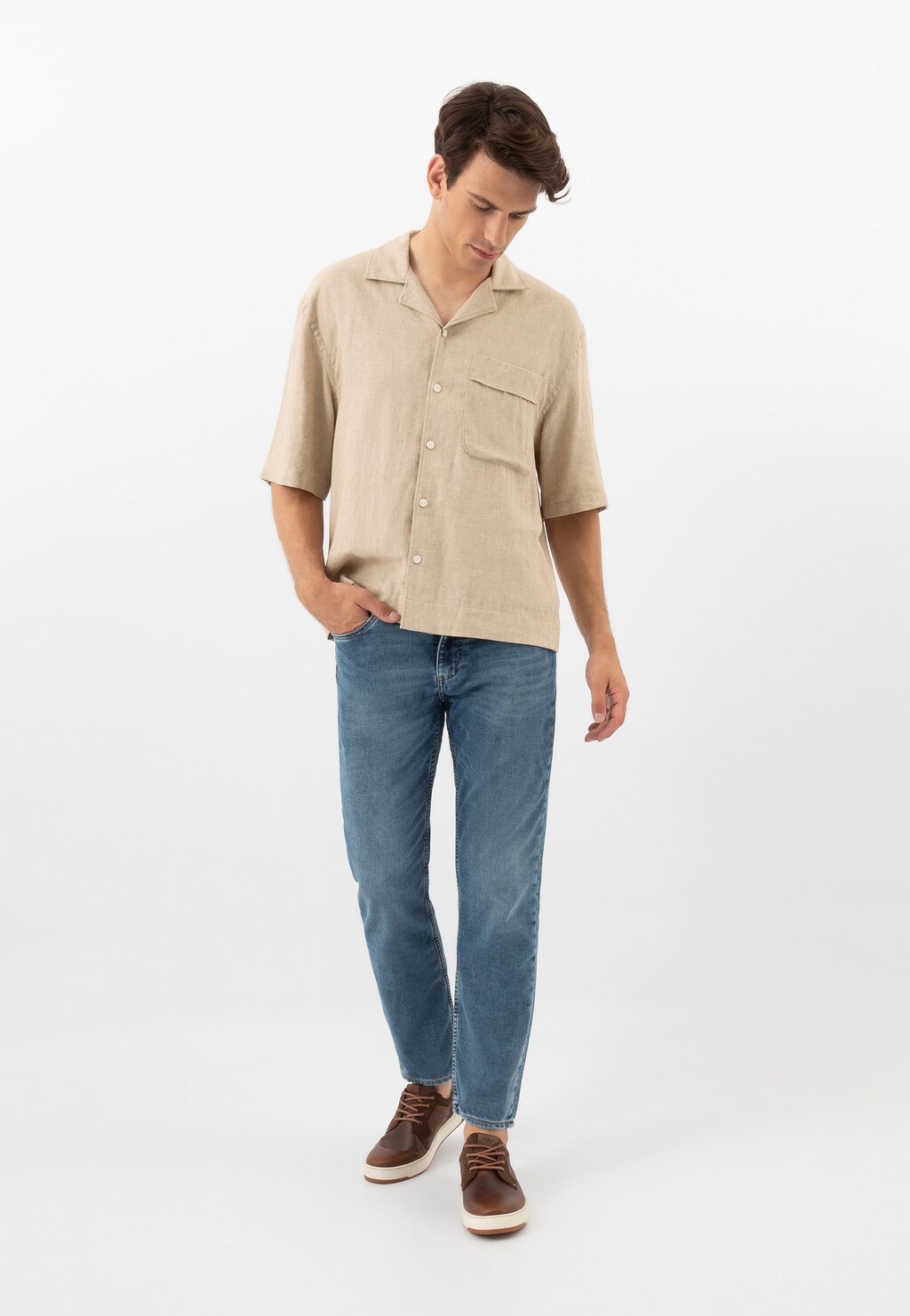 Model w beżowej koszuli i jeansach prezentuje brązowe trampki Wojas 10220-72 wykonane z łączonych skór na białej podeszwie, stylowe obuwie do codziennych stylizacji.