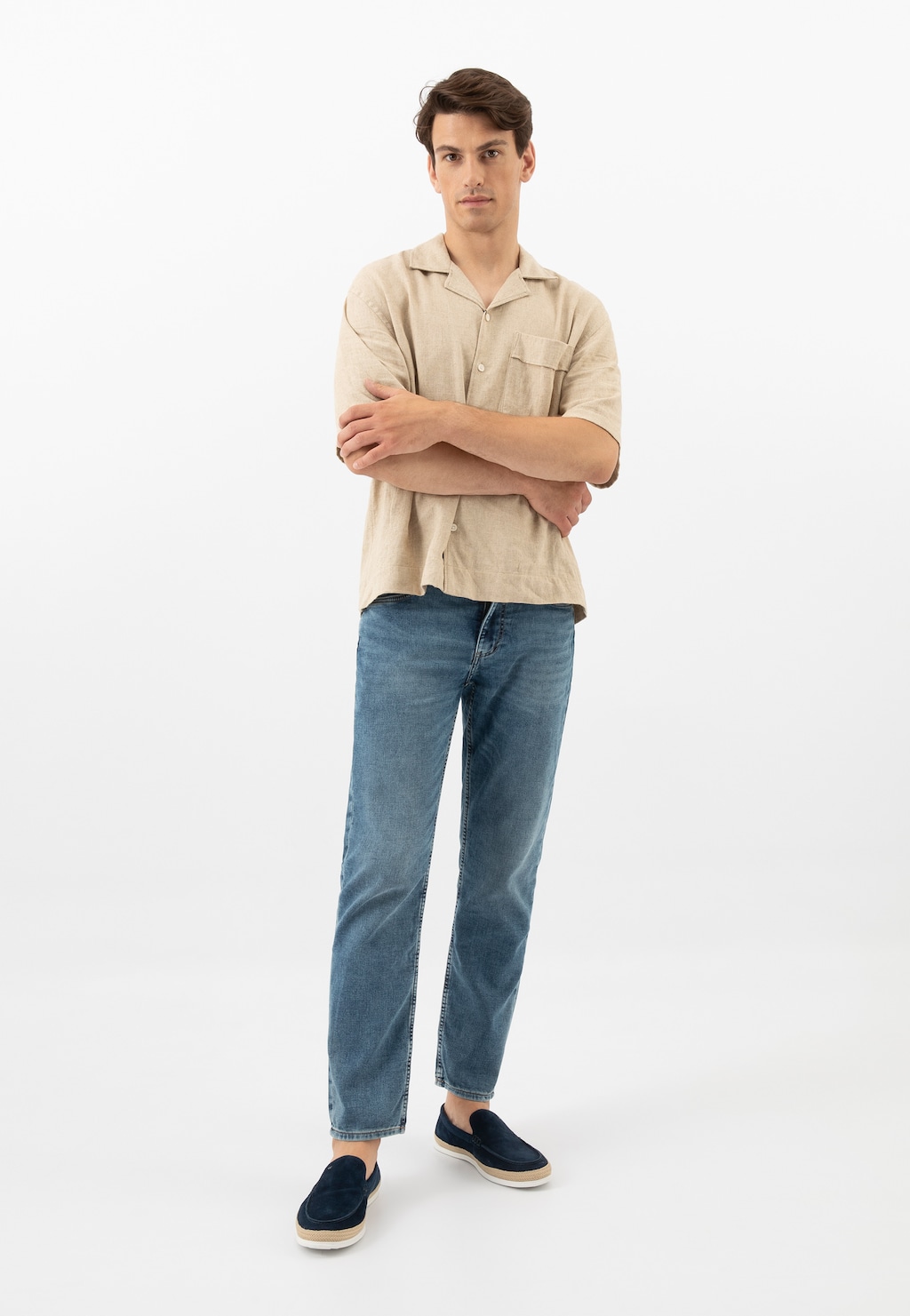 Model ubrany w beżową koszulę i jeansy, prezentujący granatowe mokasyny męskie Wojas model 10219-66 z ozdobnym jutowym sznurkiem.