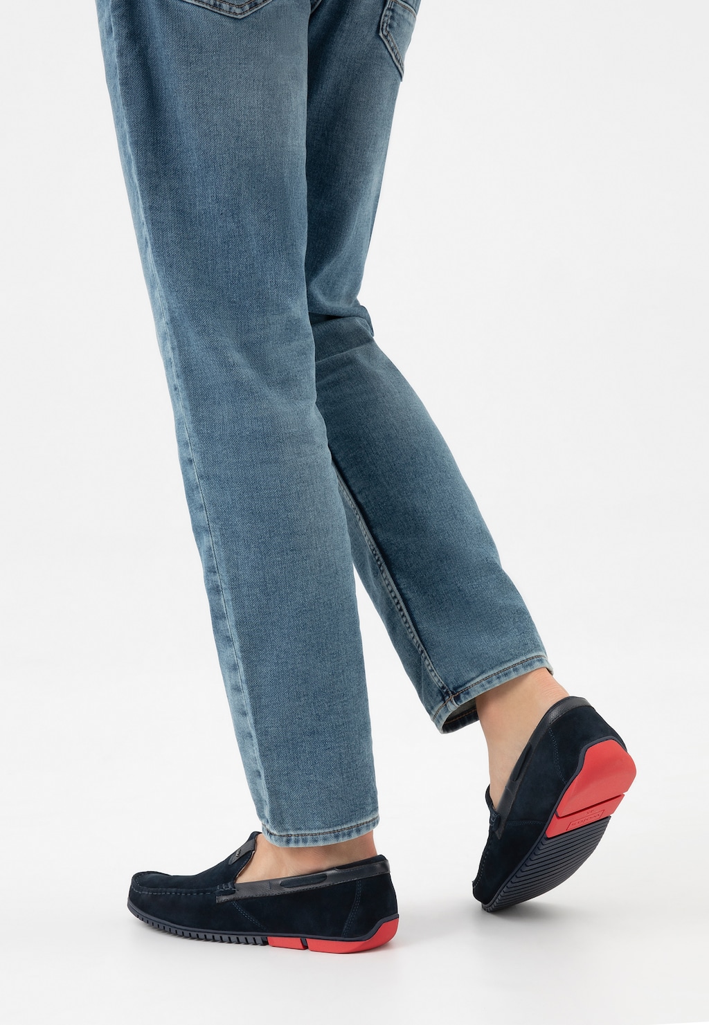 Granatowe mokasyny męskie Wojas model 10190-76 z charakterystycznymi czerwonymi akcentami na podeszwie, noszone do jasnoniebieskich jeansów, pokazane od tyłu.