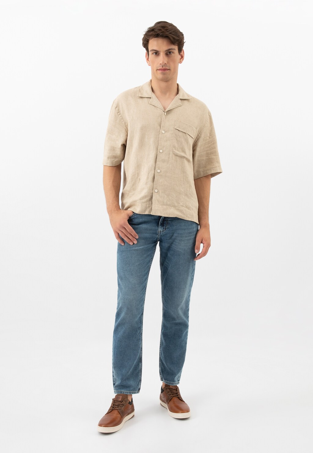 Model w beżowej koszuli i jeansach prezentuje skórzane trampki męskie Wojas 10212-72 w kolorze brązowo-granatowym, widoczne na stopach w pełnej sylwetce.