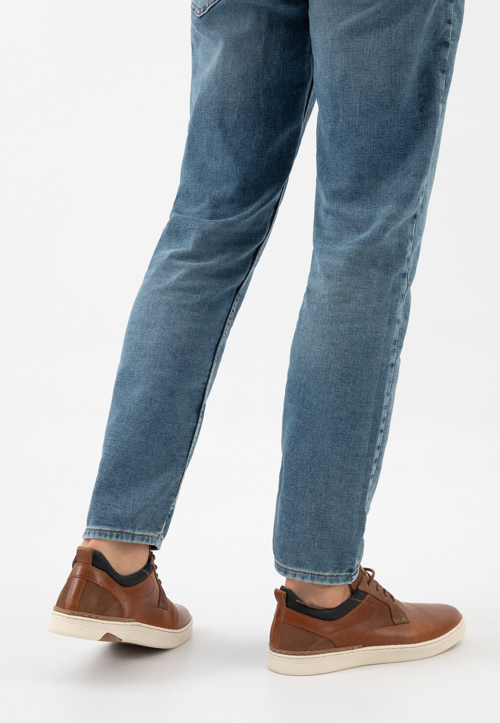 Skórzane trampki męskie Wojas 10212-72 w brązowo-granatowym kolorze, widoczne na nogach w niebieskich jeansach, z kremową podeszwą i czarnymi akcentami.