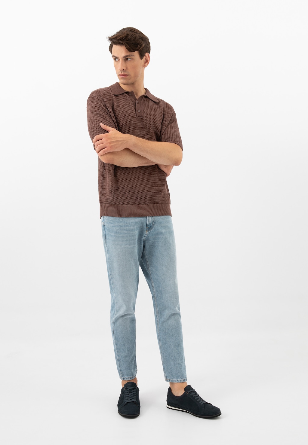 Model w brązowej koszulce polo i jasnych jeansach prezentujący granatowe półbuty męskie Wojas z linii Comfort model 10193-26, z rękami skrzyżowanymi na piersi.