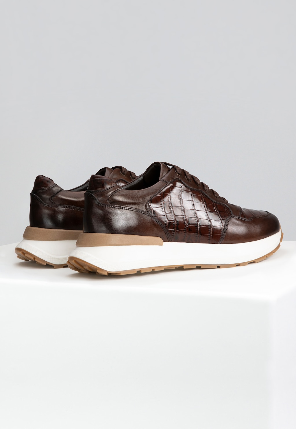 Brązowe skórzane sneakersy męskie Wojas model 10214-52 z eleganckim tłoczeniem krokodylej skóry, na grubej biało-beżowej podeszwie, widok z boku.