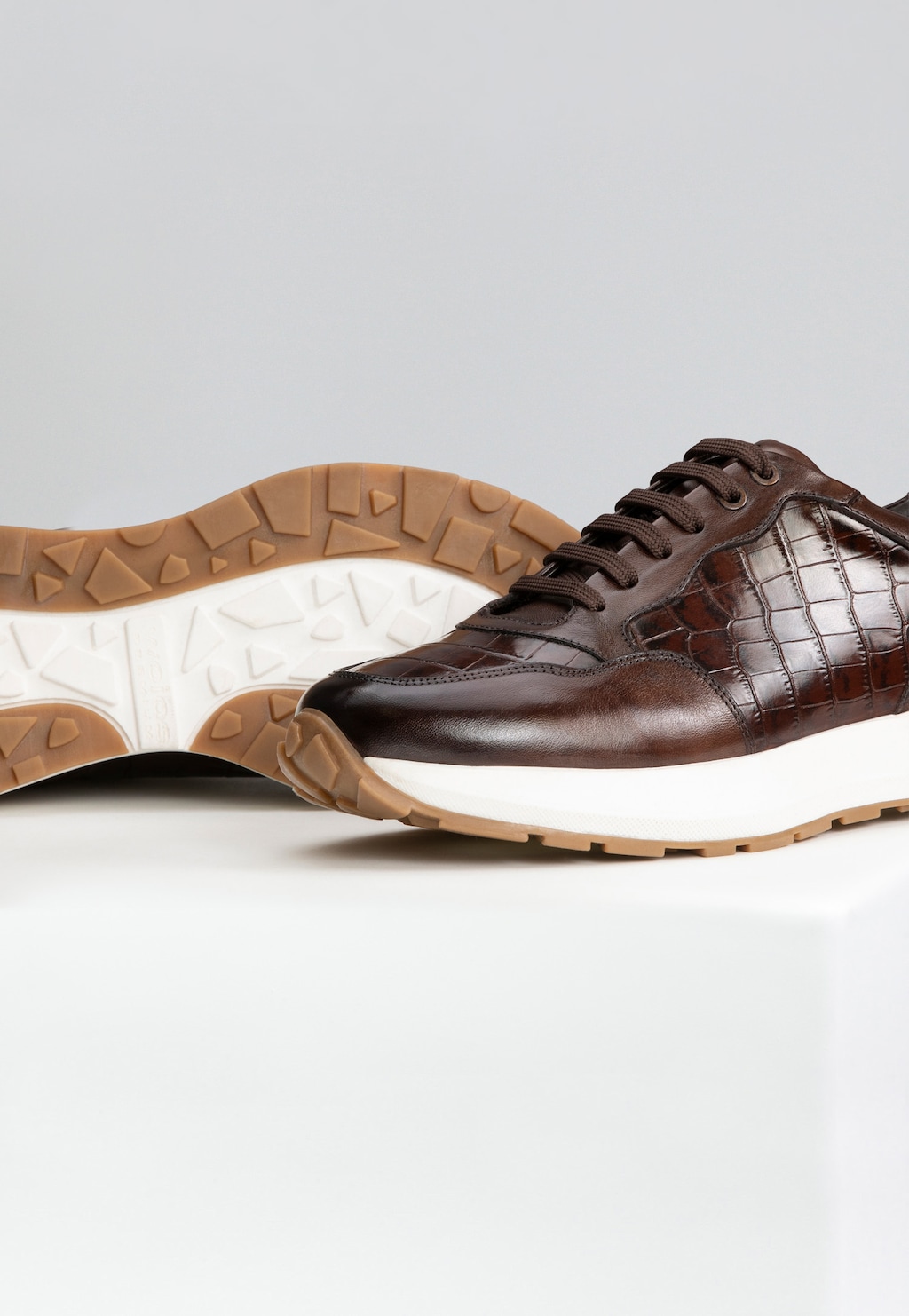 Brązowe sneakersy męskie Wojas PREMIUM 10214-52 z eleganckim tłoczeniem imitującym skórę krokodyla, na białej podeszwie z brązowym bieżnikiem.