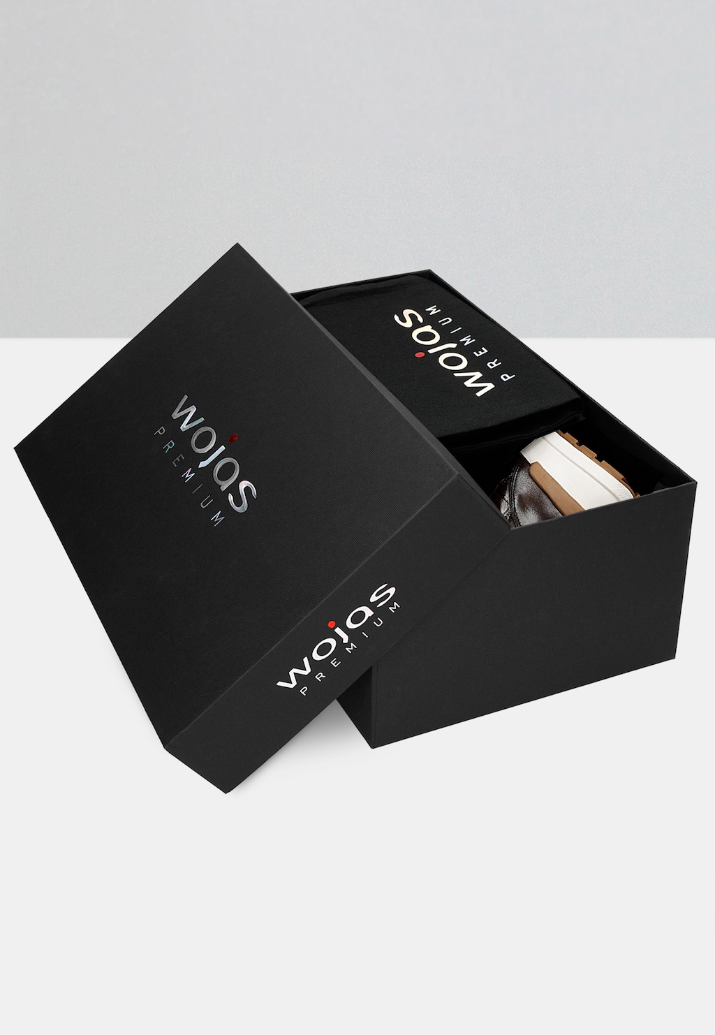 Eleganckie czarne pudełko Wojas PREMIUM z częściowo otwartym wieczkiem, wewnątrz widoczne brązowe sneakersy męskie model 10214-52 z tłoczeniem i jasną podeszwą.