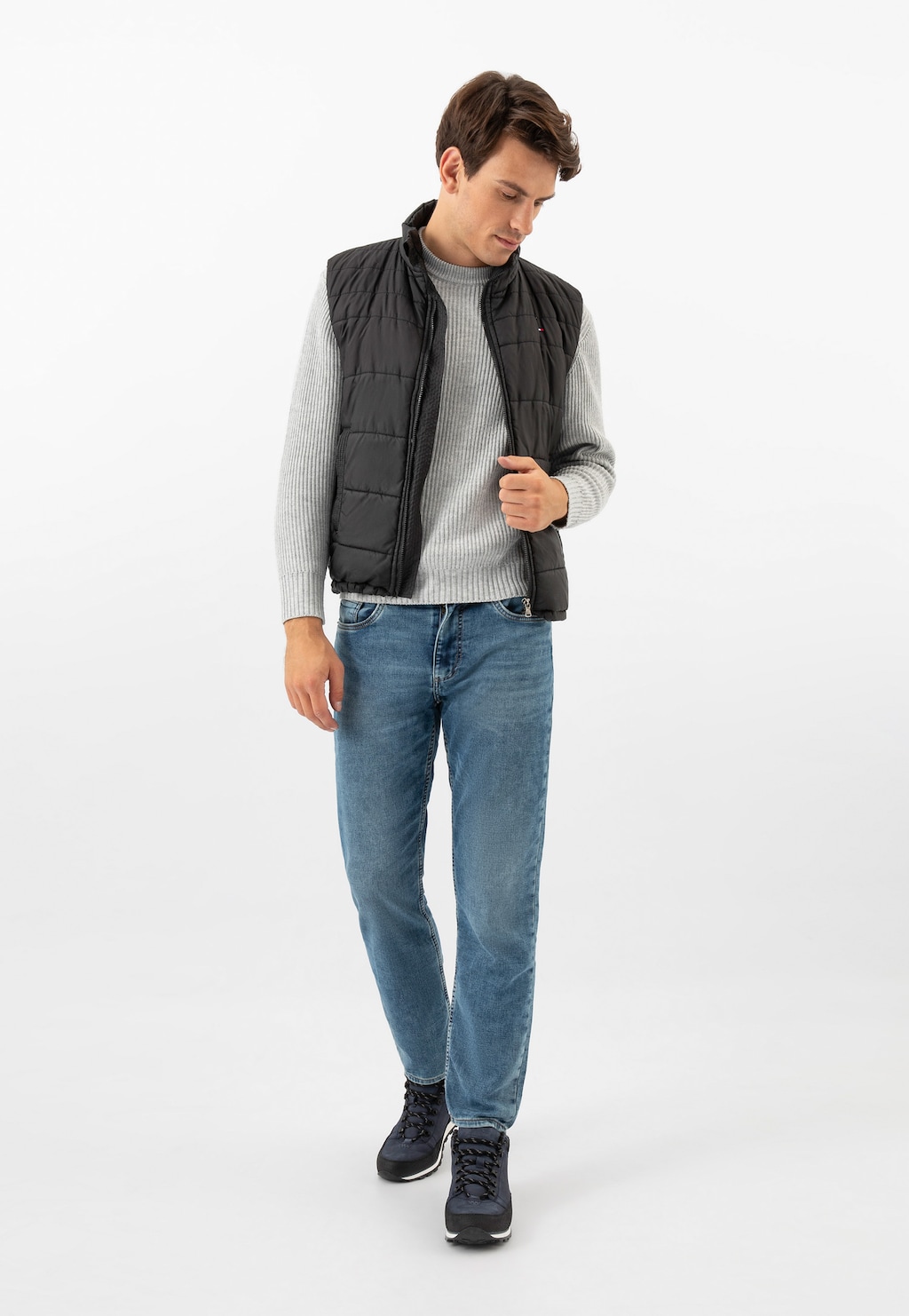 Model w casualowym stroju prezentujący granatowe trzewiki męskie Wojas 9181-76, widoczne na stopach. Stylizacja z czarną kamizelką, szarym swetrem i jeansami.