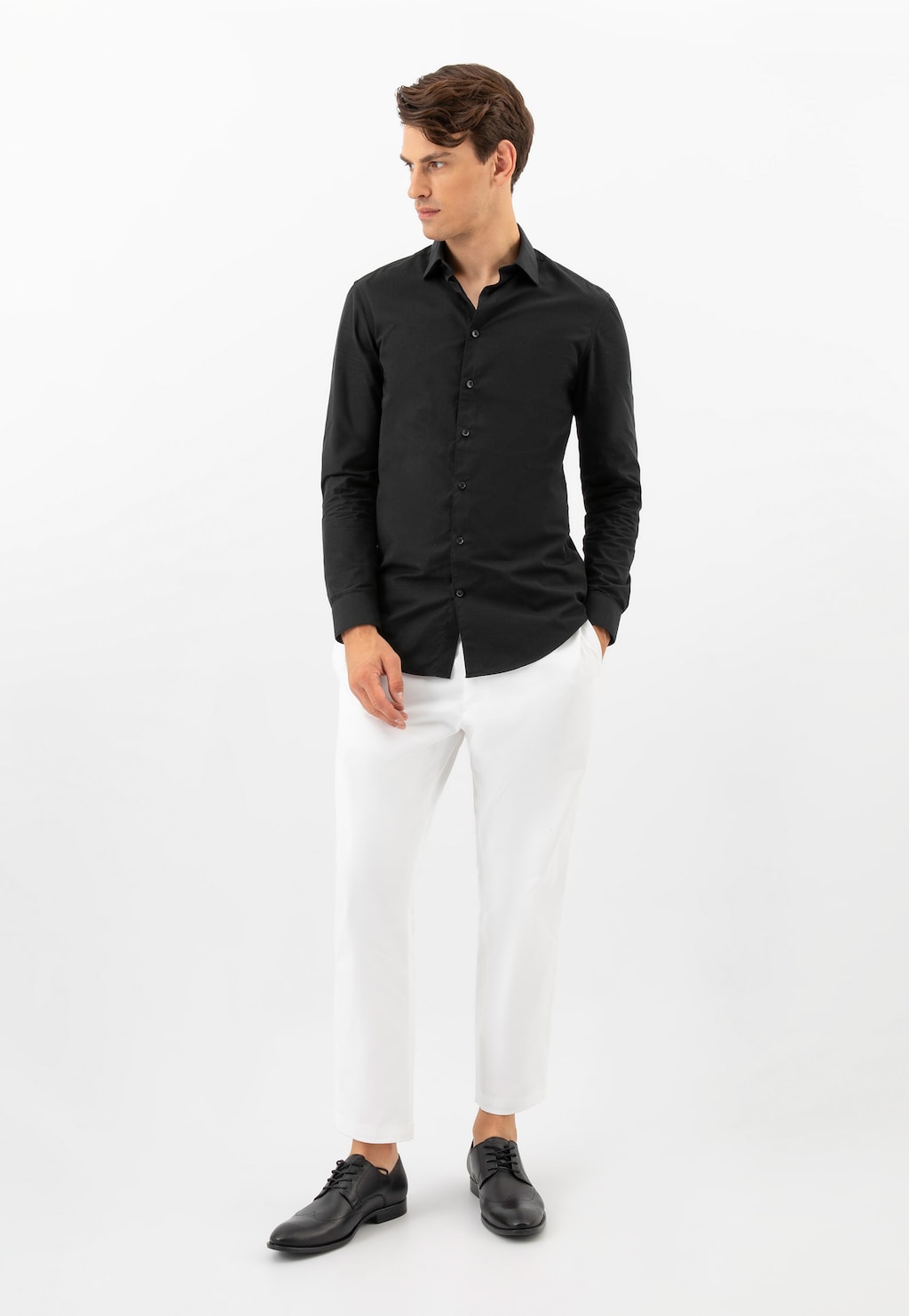 Model w eleganckim stroju z czarną koszulą i białymi spodniami, prezentujący czarne eleganckie buty Wojas ze skóry licowej model 10195-51.