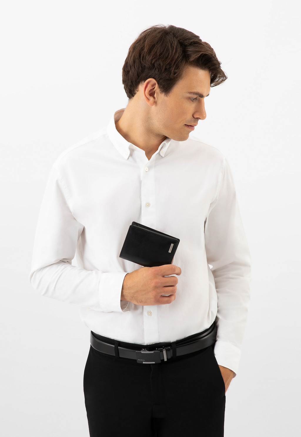 Mężczyzna w białej koszuli trzymający czarny portfel męski Wojas model 7941-51. Elegancki, biznesowy wygląd z czarnymi spodniami i paskiem.