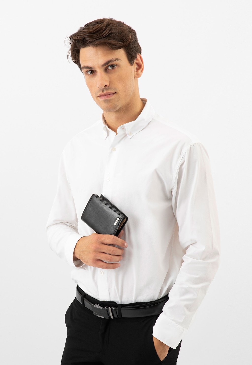Model w białej koszuli trzymający czarny portfel męski Wojas model 7941-51, ubrany w eleganckie czarne spodnie z paskiem, prezentujący funkcjonalny dodatek.