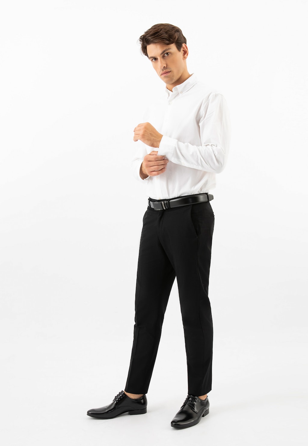 Model w eleganckiej stylizacji prezentuje czarne męskie półbuty Wojas 9040-51, idealne do formalnego stroju z białą koszulą i czarnymi spodniami.