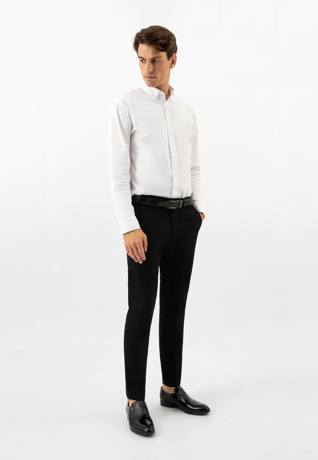 Model w eleganckiej stylizacji - biała koszula i czarne spodnie - prezentujący eleganckie skórzane mokasyny męskie Wojas model 10225-51 w kolorze czarnym.