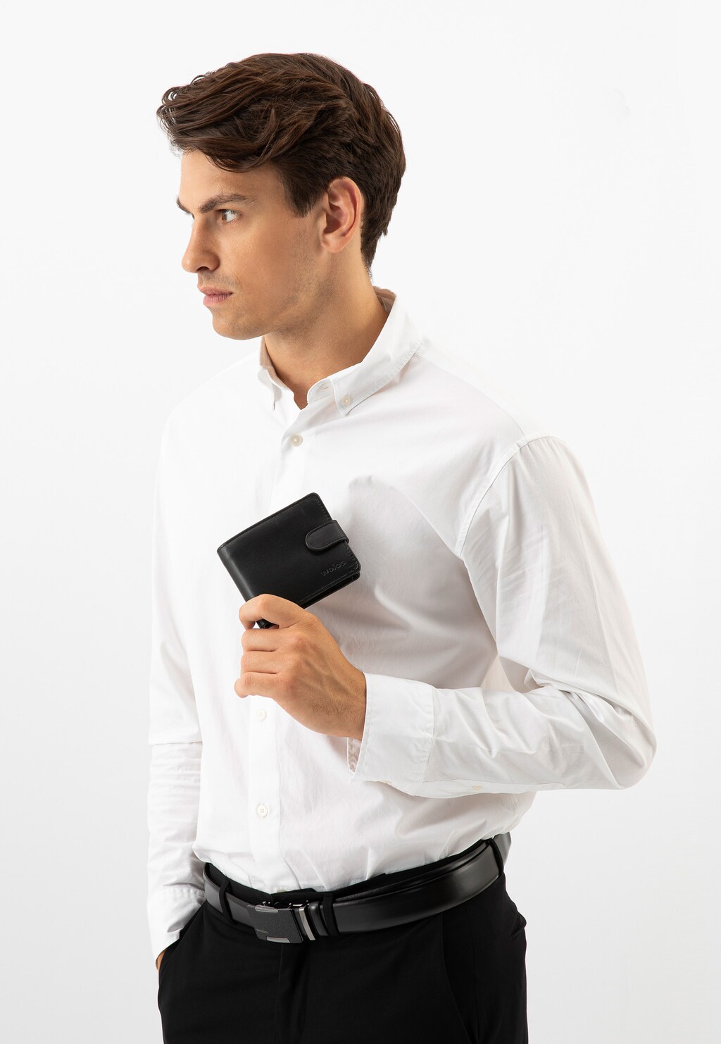 Elegancki mężczyzna w białej koszuli trzymający czarny portfel Wojas model 91047-51 z zapięciem na zatrzask. Stylowa prezentacja produktu w biznesowym kontekście.