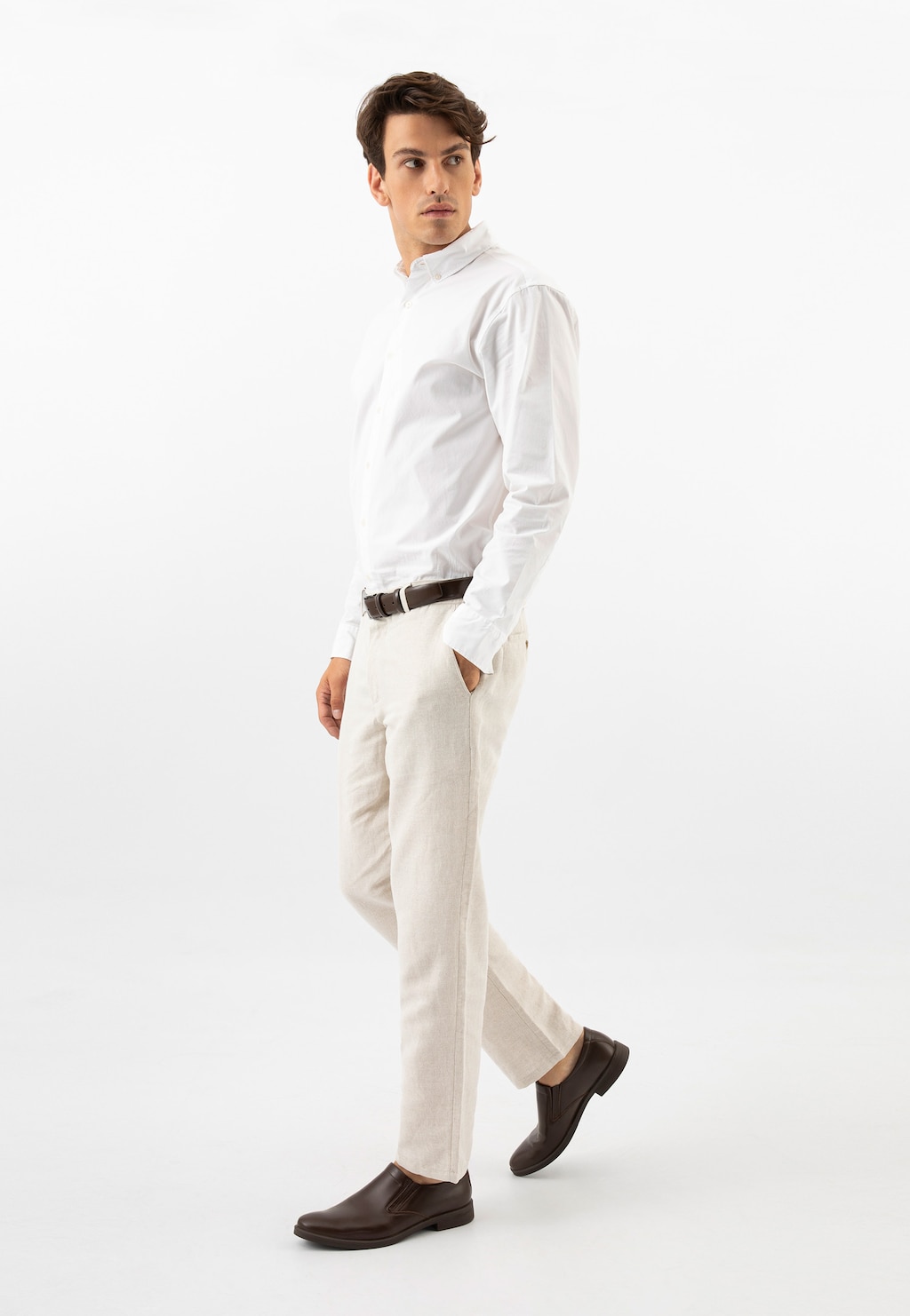 Model w eleganckim stroju z brązowymi wsuwanymi półbutami Wojas 10221-52 ze skóry licowej, idealnymi do jasnych spodni i białej koszuli.