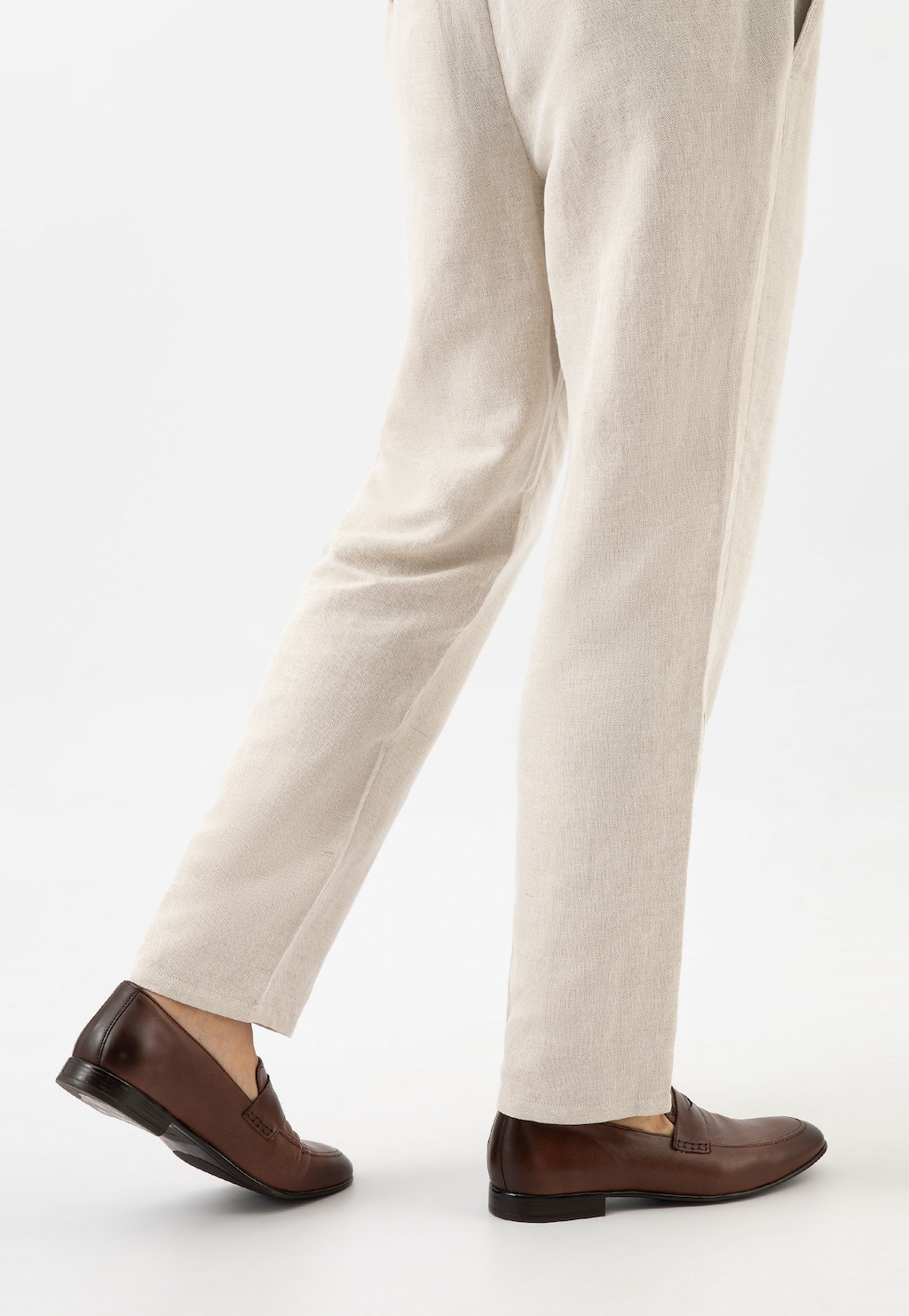 Eleganckie brązowe loafersy męskie Wojas model 10152-53 z naturalnej skóry, prezentowane na nodze w jasnych lnianych spodniach, idealne do stylizacji biznesowych.
