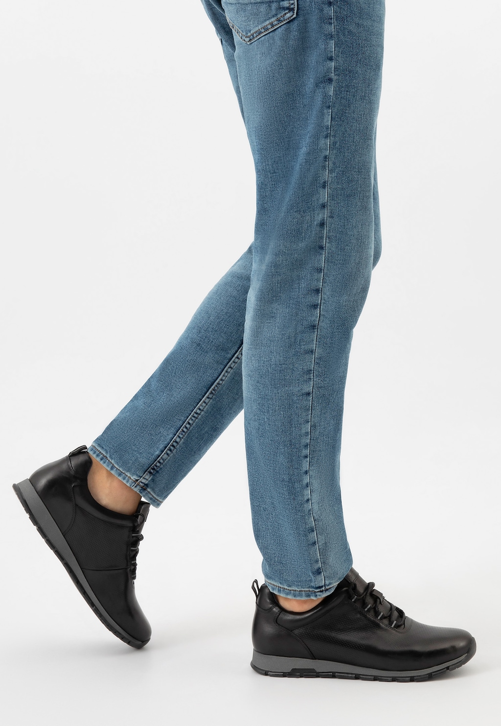 Czarne sneakersy męskie Wojas model 10039-51 ze skóry licowej noszone do jeansów. Eleganckie, sportowe buty z szarą podeszwą, idealne do codziennych stylizacji.