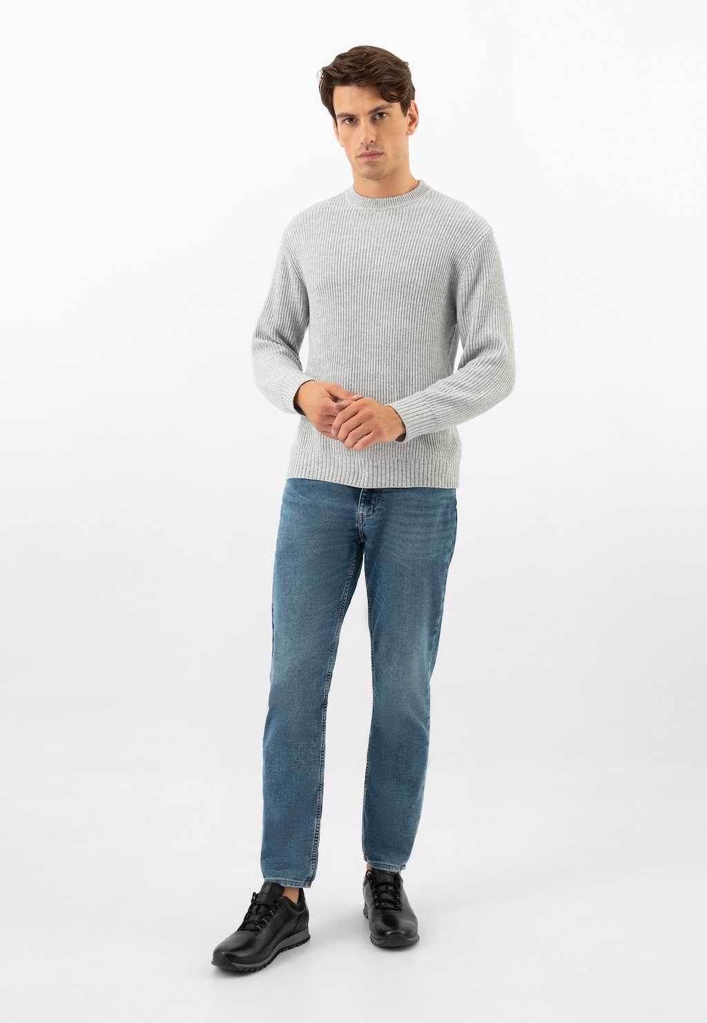 Model prezentuje czarne sneakersy męskie Wojas 10039-51 ze skóry licowej. Stylizacja z szarym swetrem i jeansami podkreśla casualowy charakter obuwia.