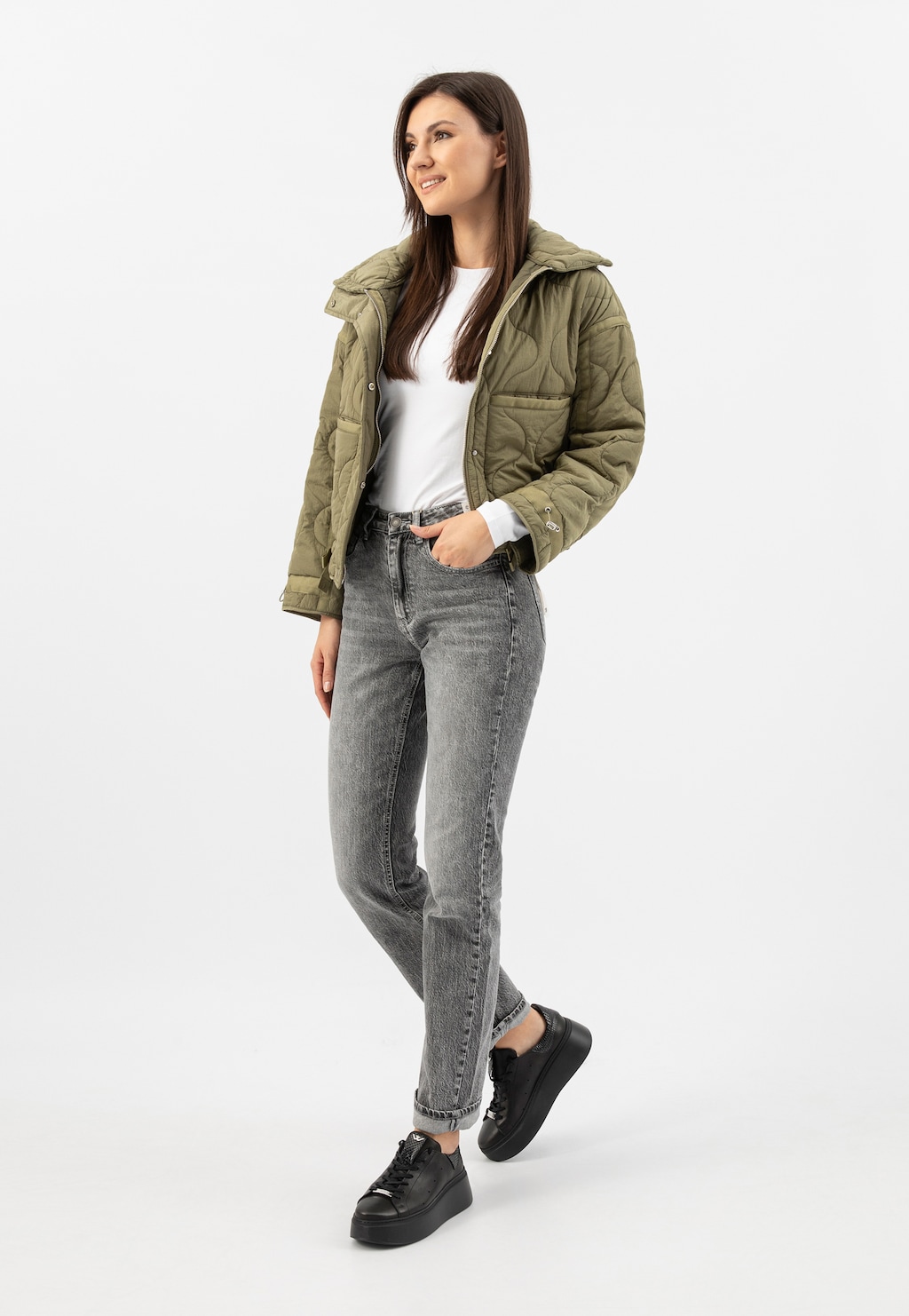 Osoba w stylowej stylizacji z oliwkową kurtką puchową, szarymi jeansami i czarnymi trampkami Wojas model 46285-51 na wysokiej podeszwie.