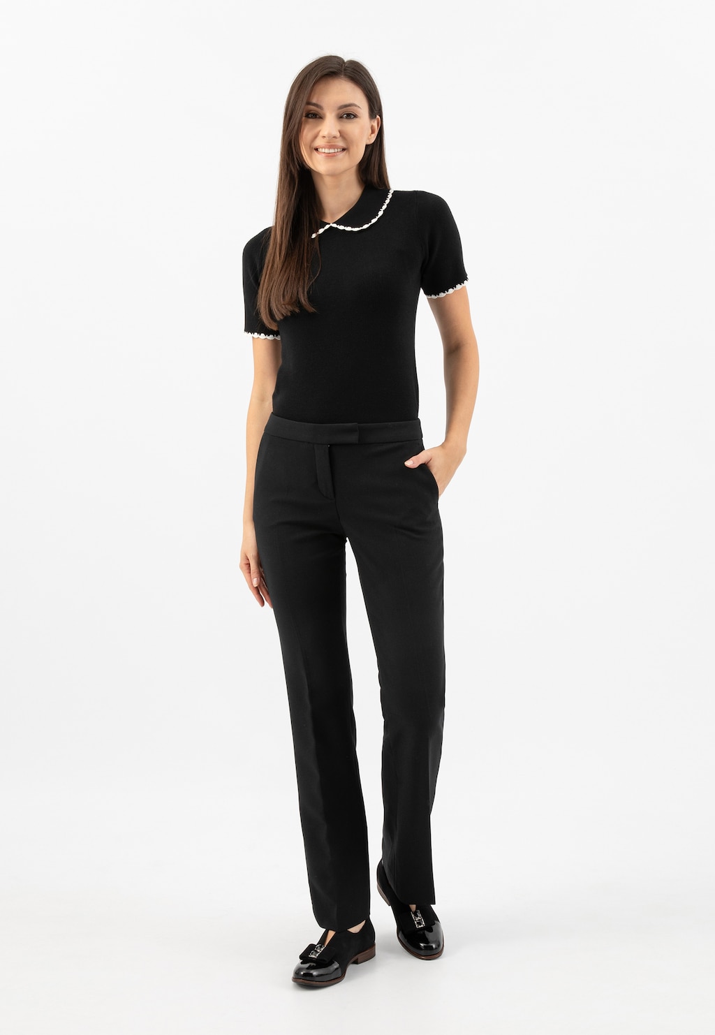 Elegancki czarny strój z koszulką z białym kołnierzykiem i spodniami. Na nogach czarne wsuwane półbuty damskie Wojas model 46302-71 z ozdobnym wycięciem i kokardą.