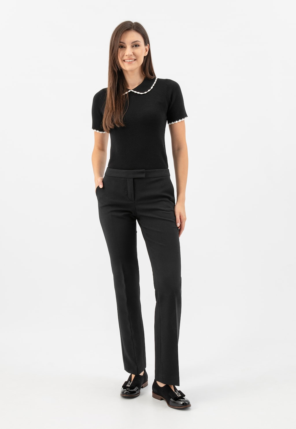 Eleganckie czarne wsuwane półbuty damskie Wojas model 46302-71 z ozdobnym wycięciem i kokardą widoczne na modelce w czarnym stroju biznesowym.