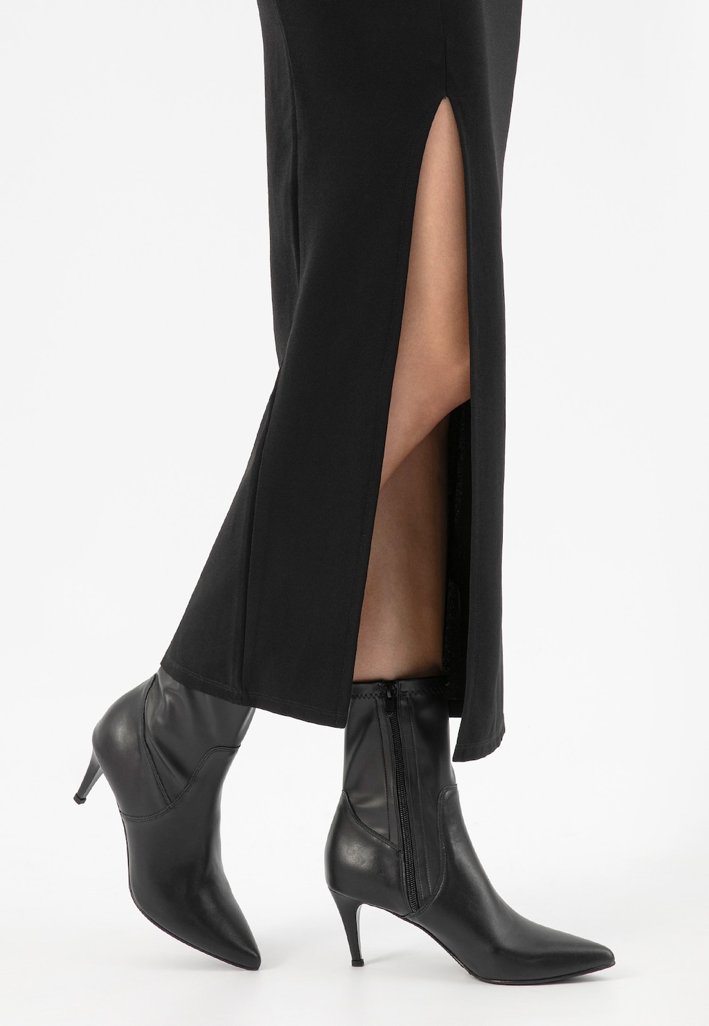 Czarne eleganckie botki Wojas model 55017-51 na szpilce zestawione z długą czarną spódnicą z wysokim rozcięciem, podkreślające smukłość nogi i elegancki styl.