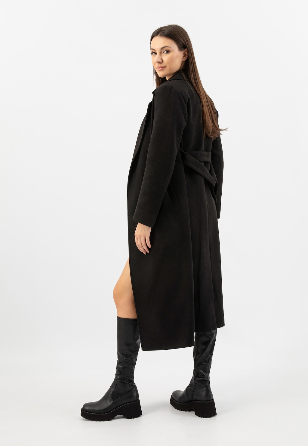 Modelka w długim czarnym płaszczu prezentuje czarne jesienne kozaki Wojas na platformie model 71065-81. Eleganckie obuwie widoczne z profilu, idealne do jesiennych stylizacji.